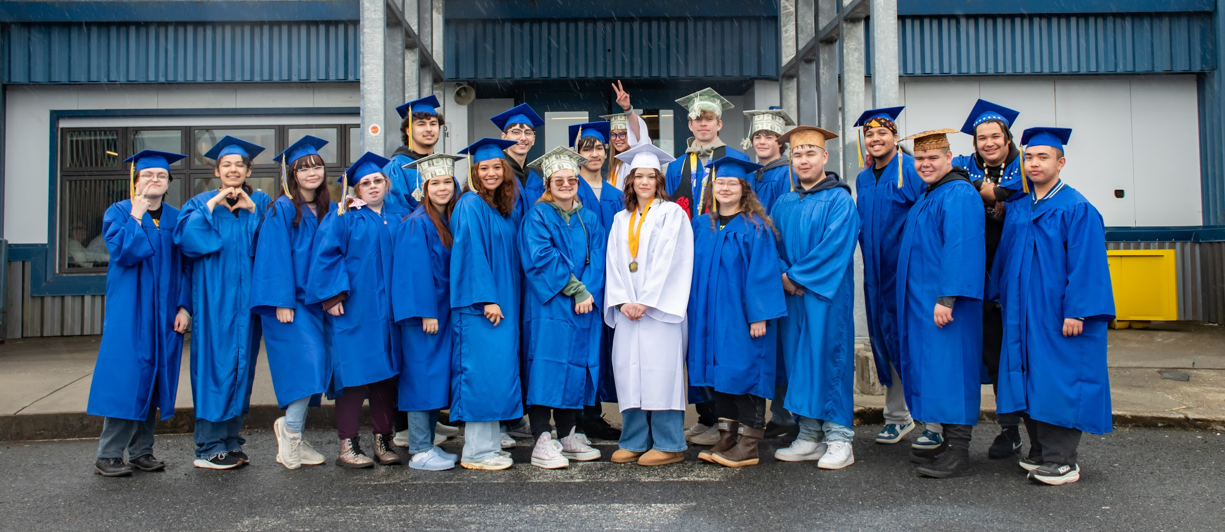 students in front of school in caps and gowns