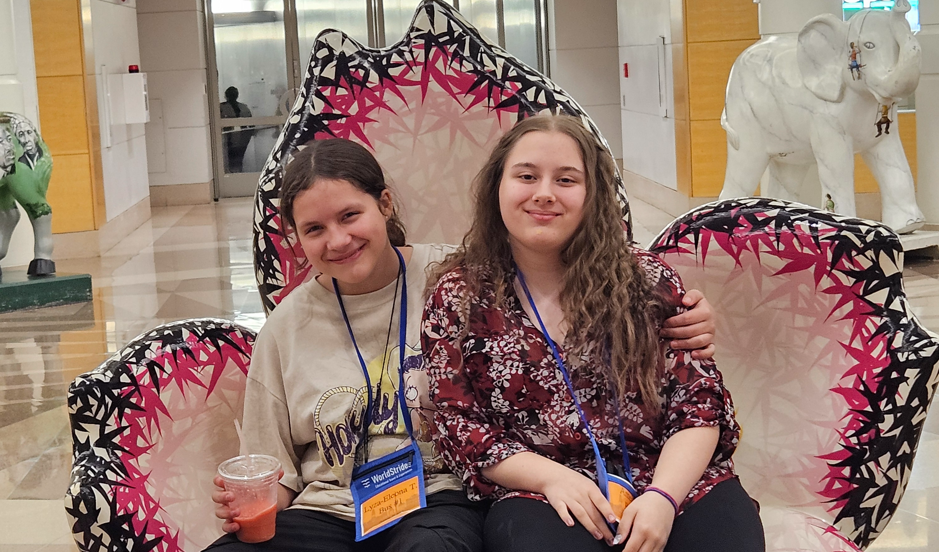 Two female students relax while sitting on  a decorative chair