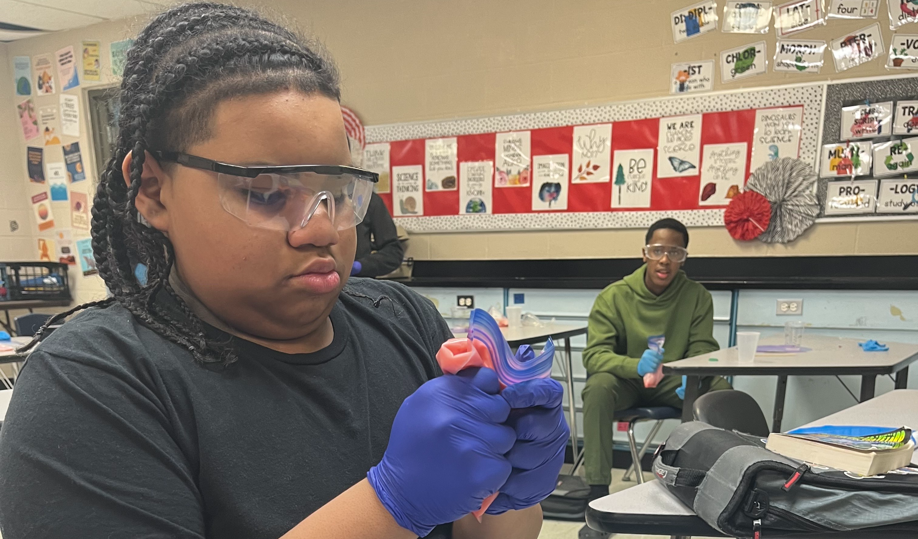 Male student wears safety glasses as he performs a science experiment.