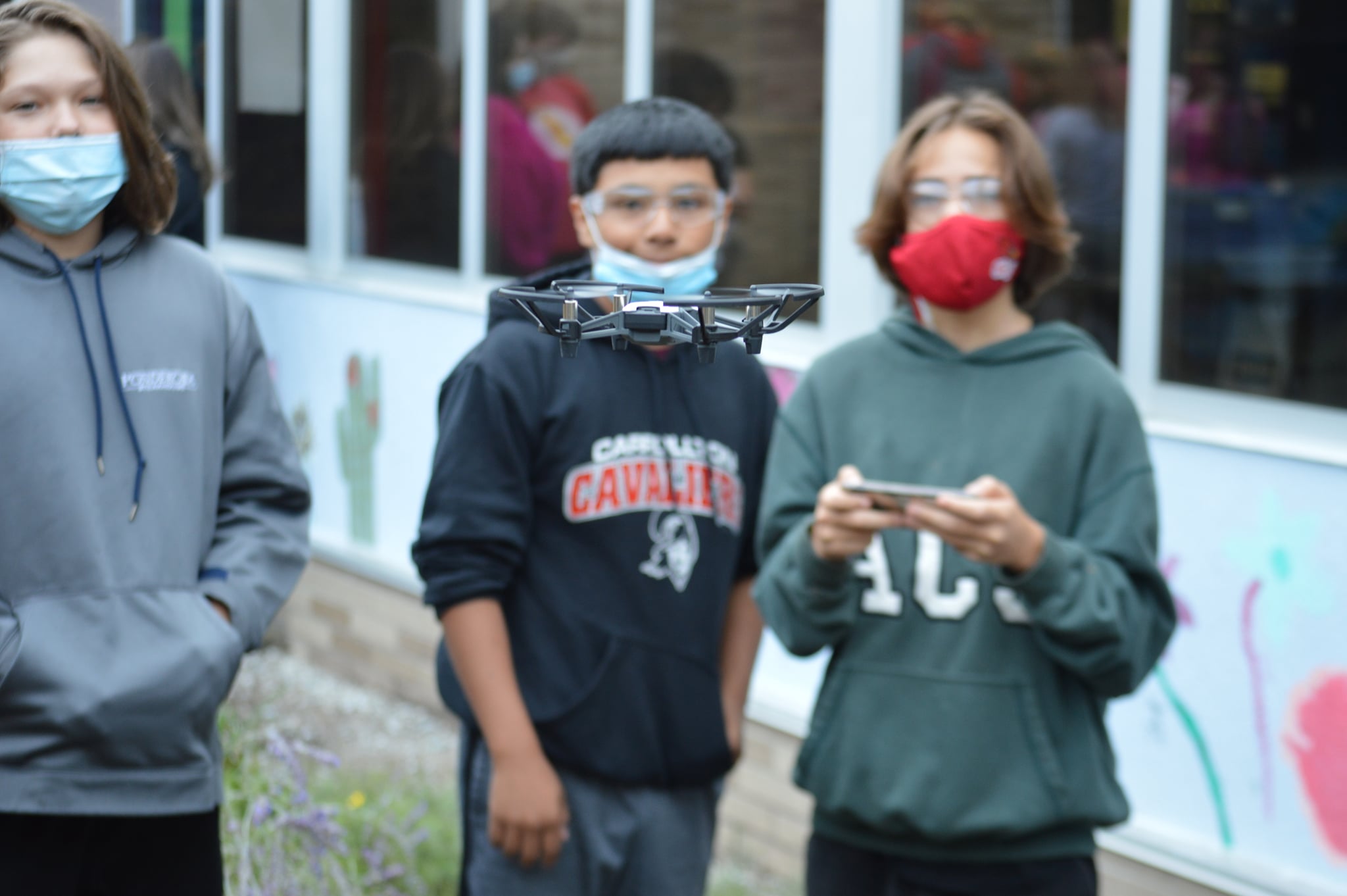 Group of students looking on while one flies a drone