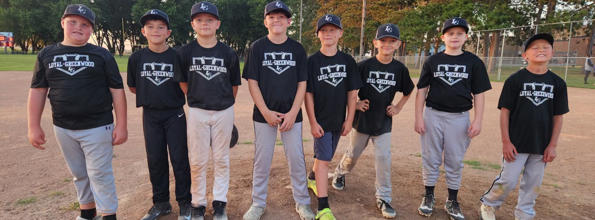 boys wearing black and gray baseball uniforms standing in a row on a baseball field