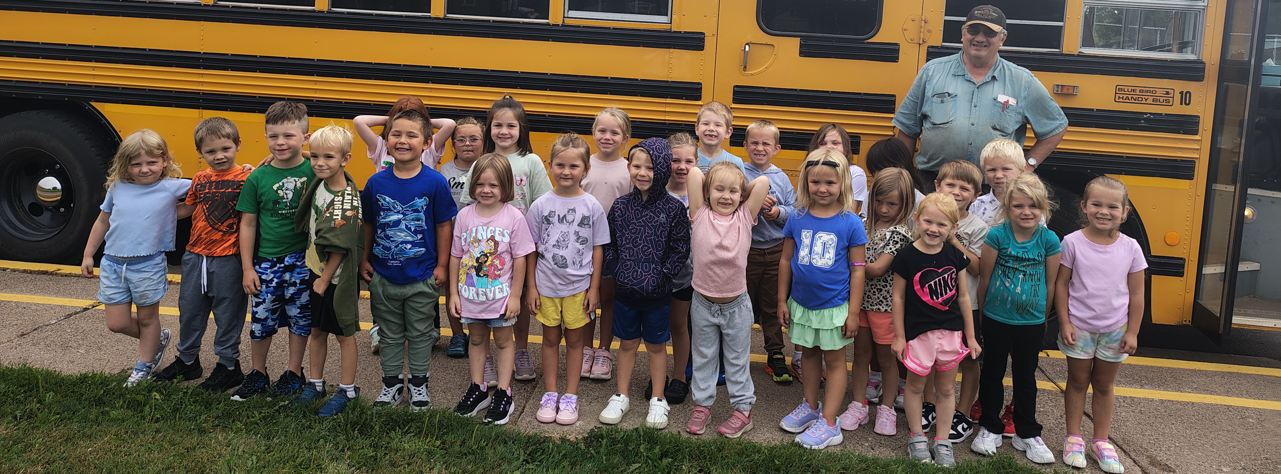 students and bus driver lined up in front of a bus 
