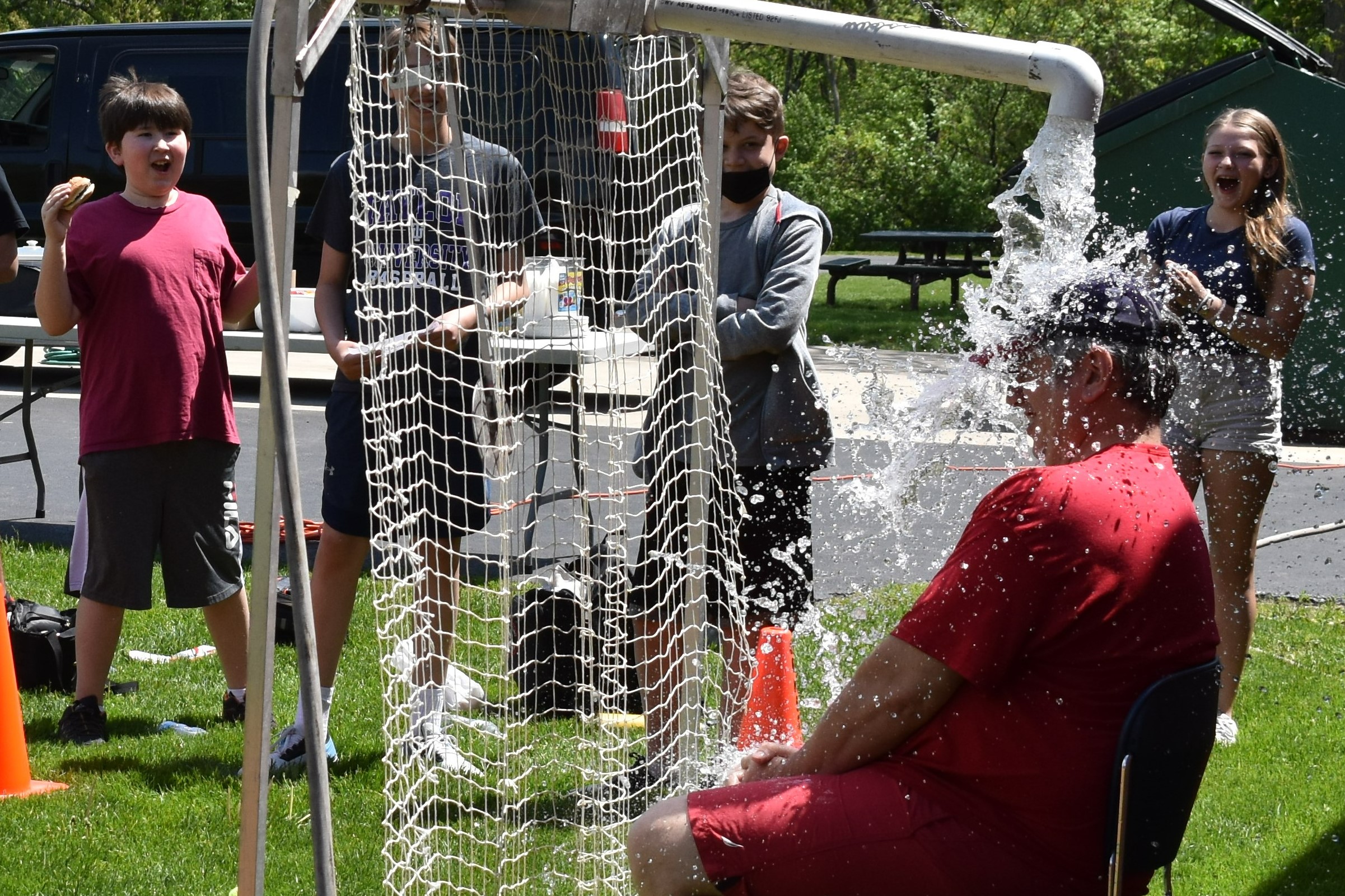 Dr. Fitzgerald getting doused with water from a reverse dunk tank while students happily watch in the background