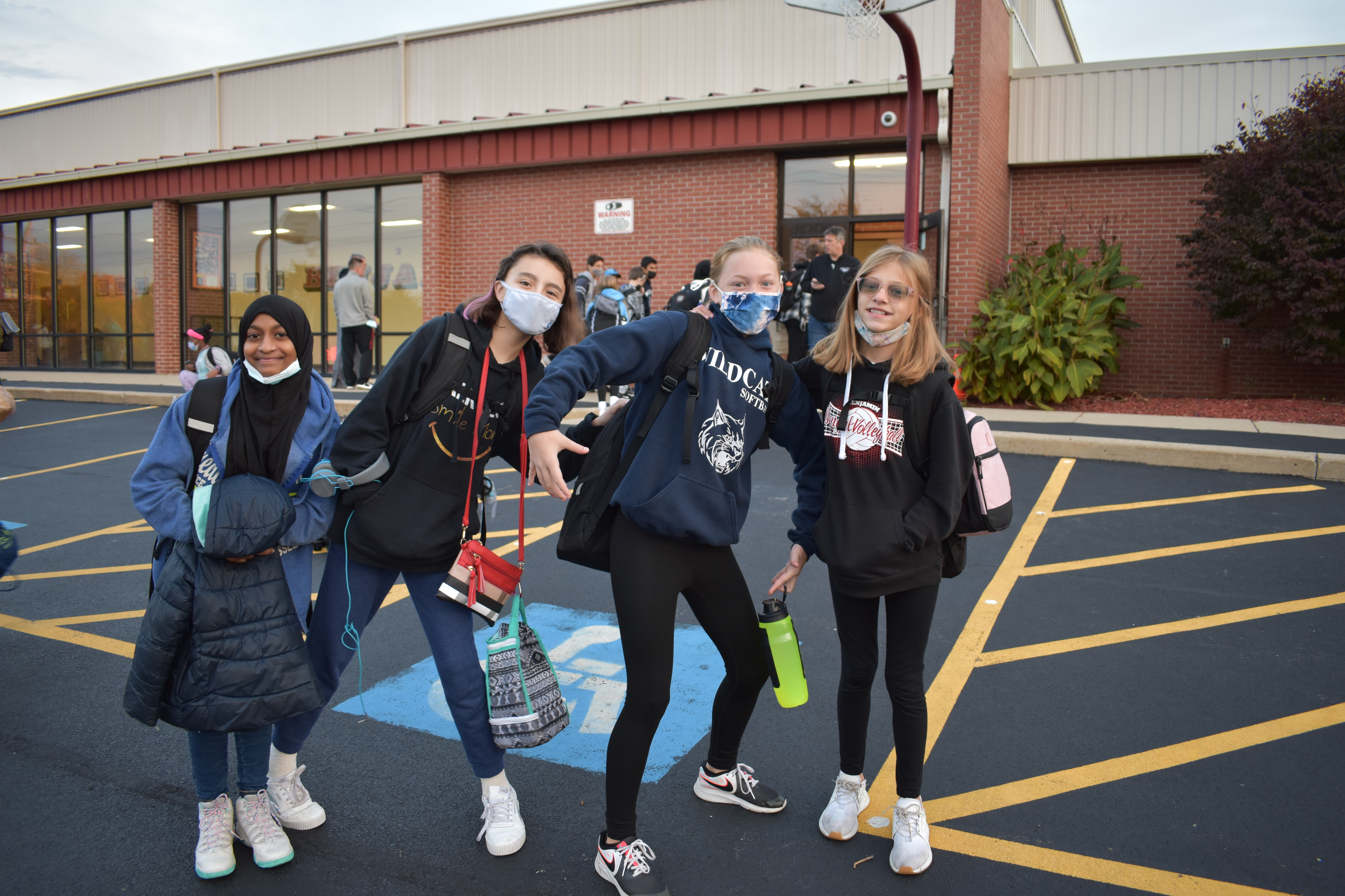 students pose and smile on the blacktop in front of the school