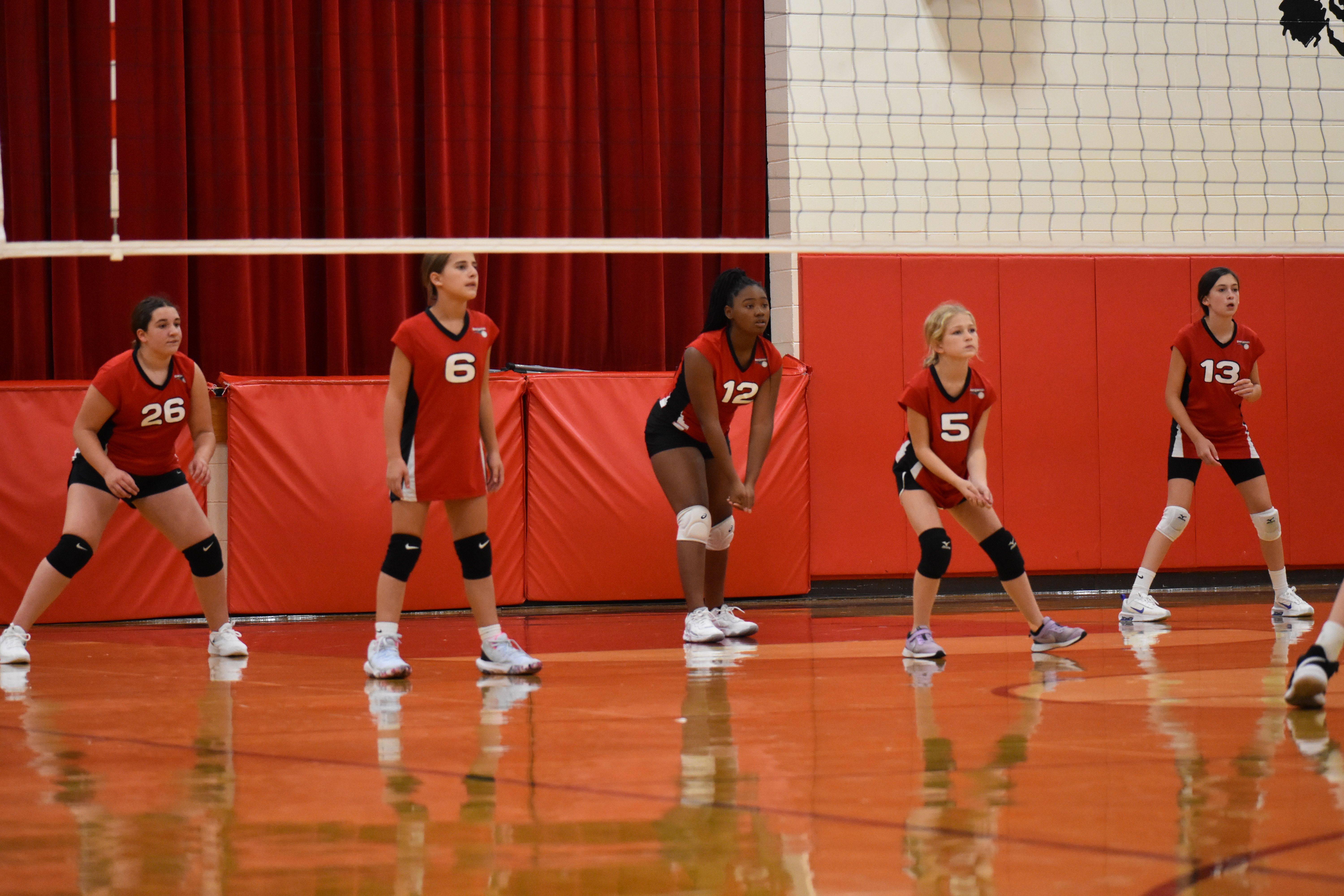 5 Benjamin JV volleyball players stand ready for the serve during a game.