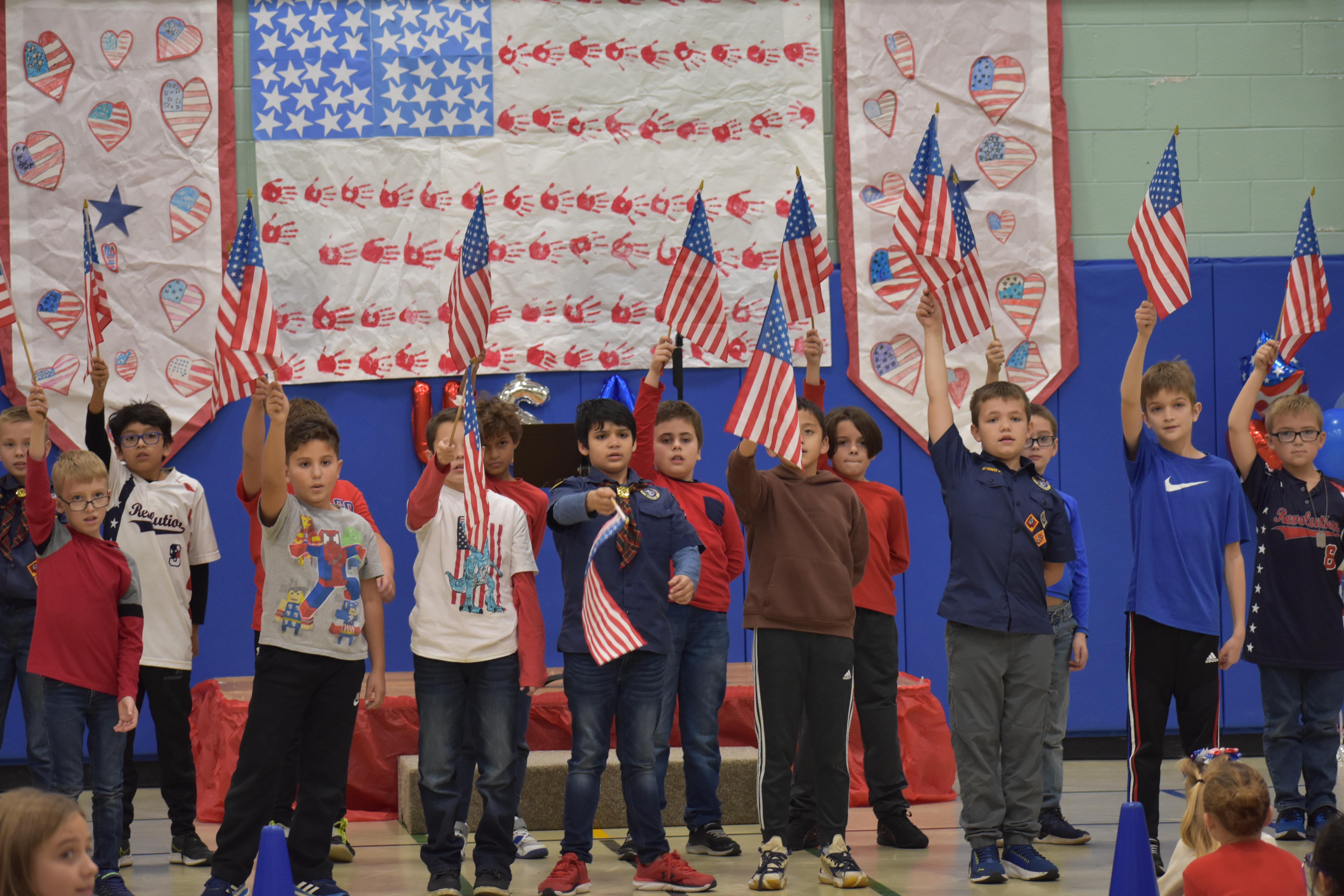 Students wearing red, white and blue  waving American flags.