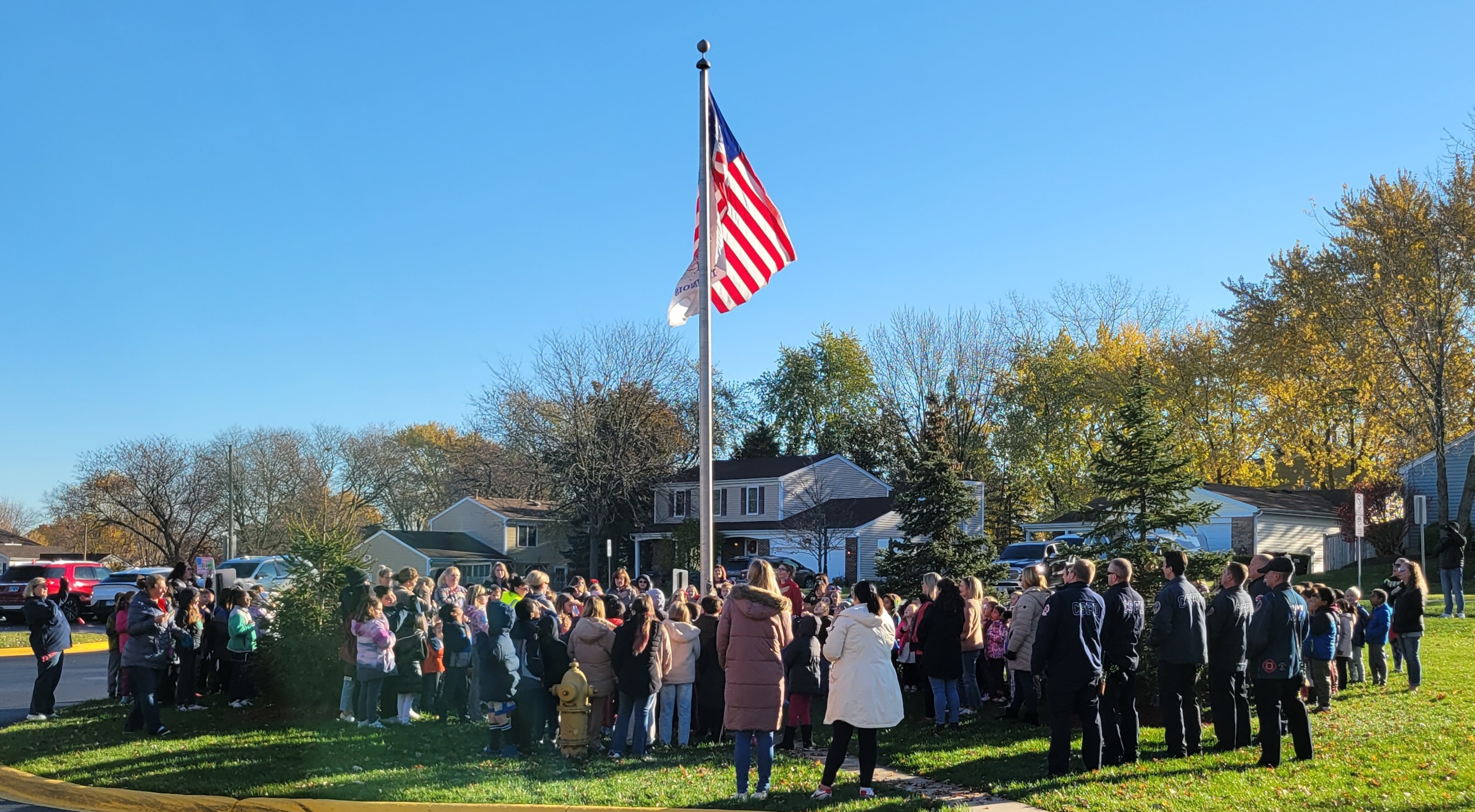 A large group of students and adults standing around a flag pole
