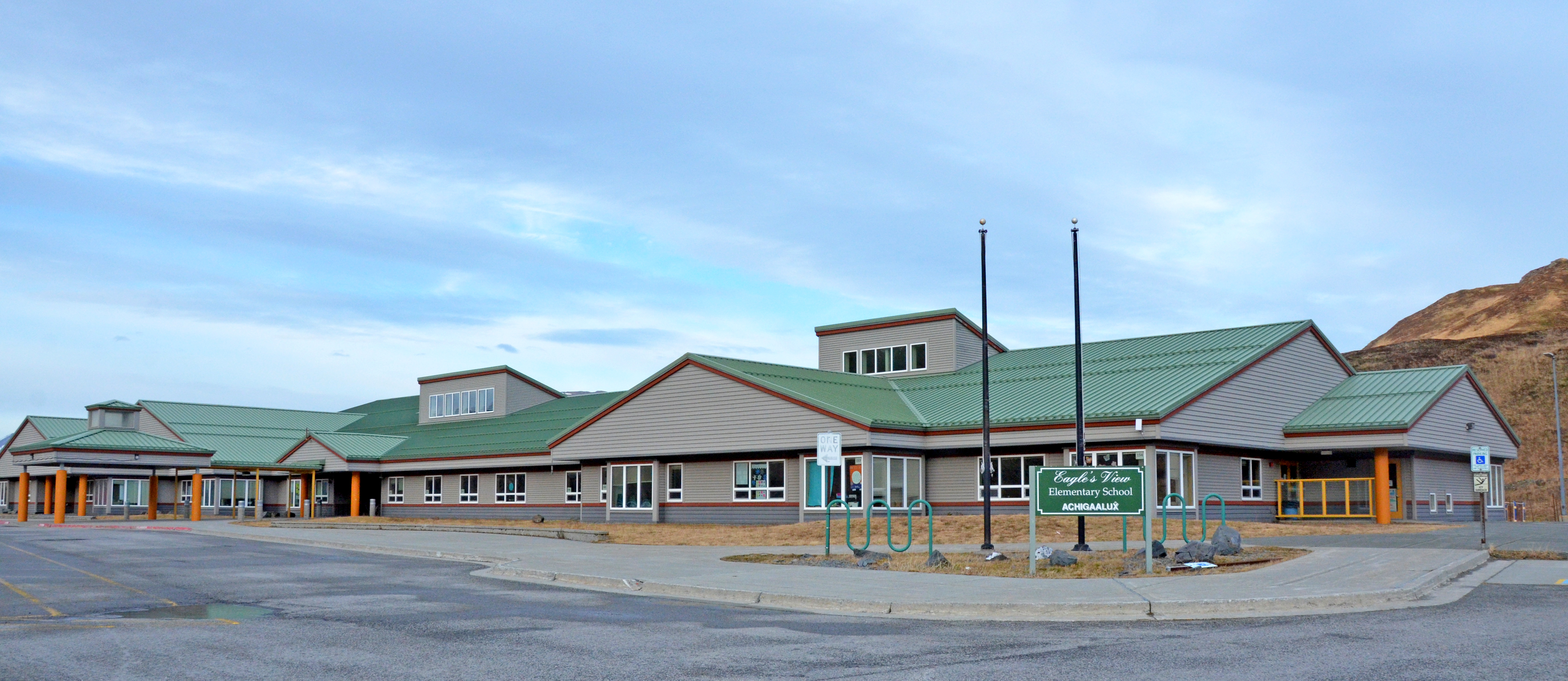 Outside view of Eagle's View Elementary School building, flag poles, some of the parking lot, and the school sign.