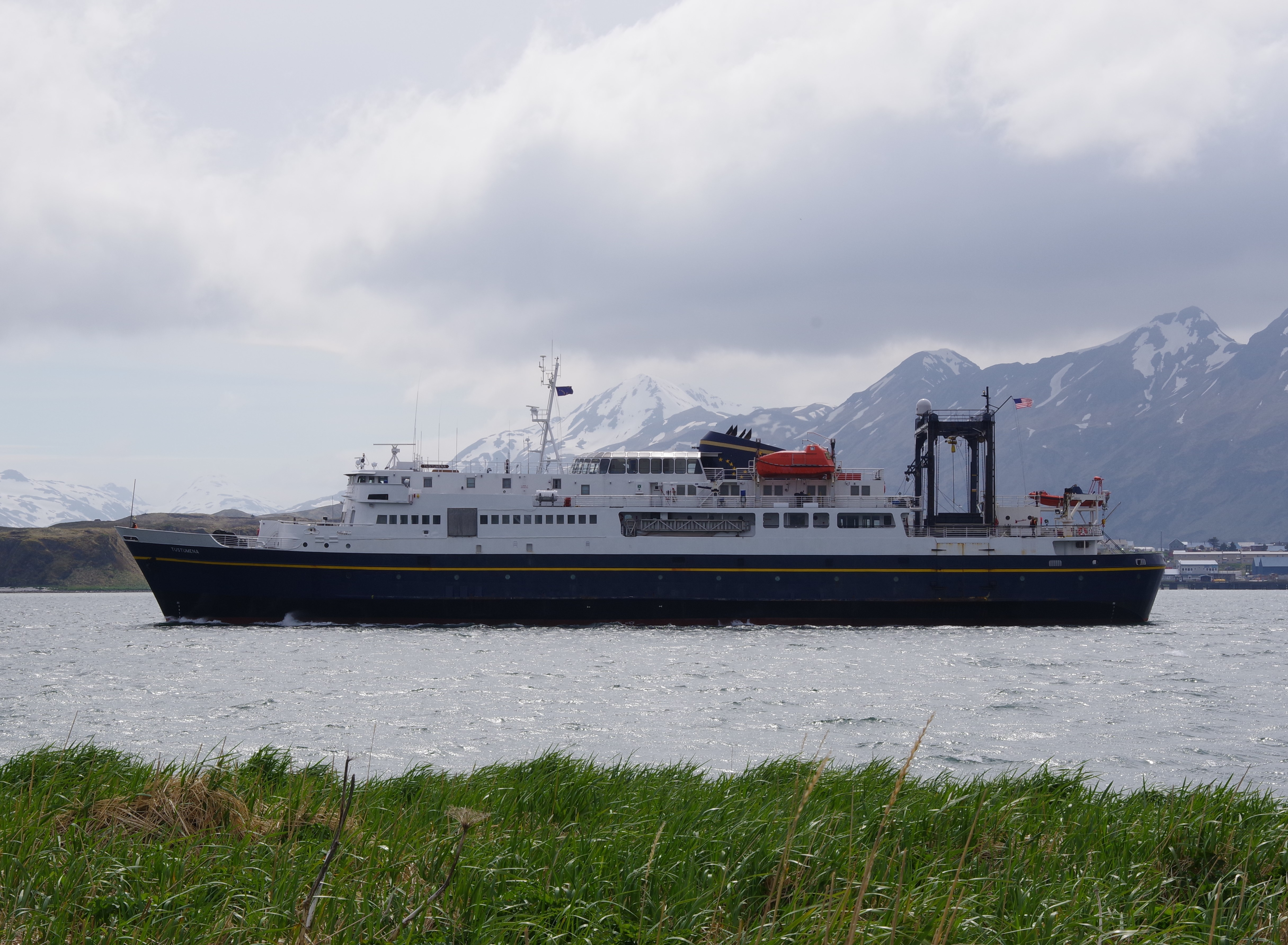 Ferry in bay with mountains and grass
