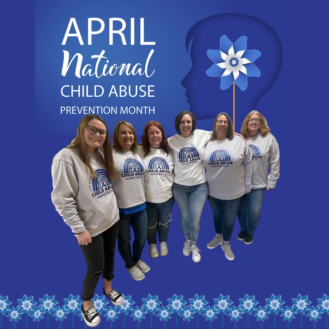 Staff members pose in Child Abuse Awareness outfits in a decorated background
