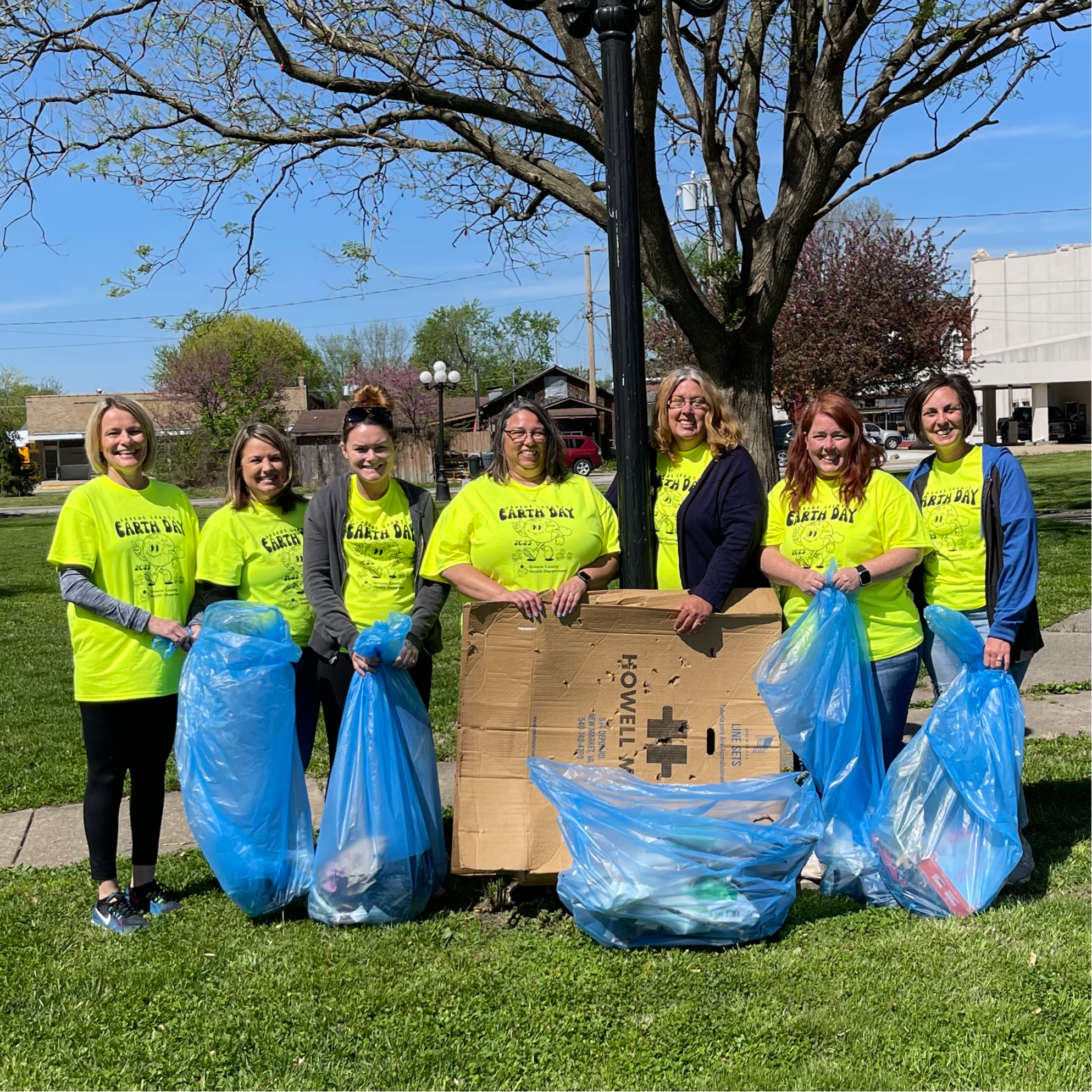 Staff pose at a park with the bags of trash that they collected for earth day