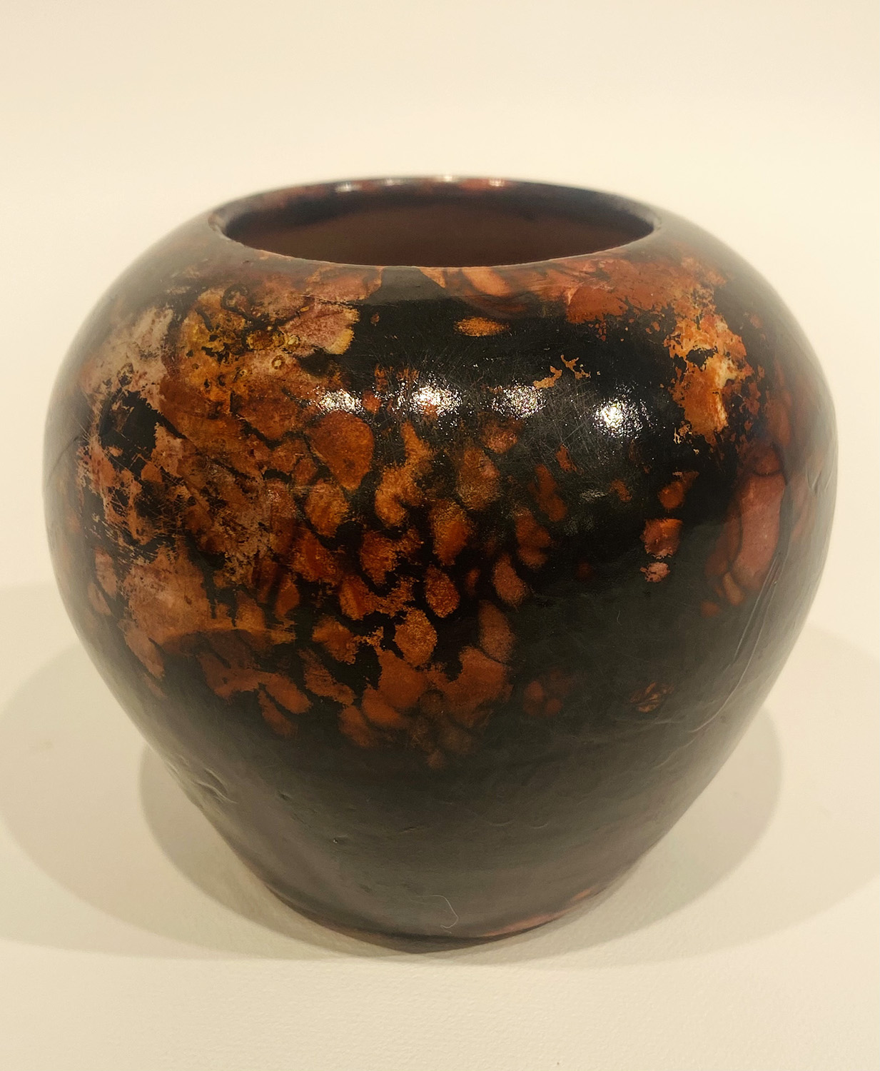 Student art of a clay pot burnished in browns and blacks.