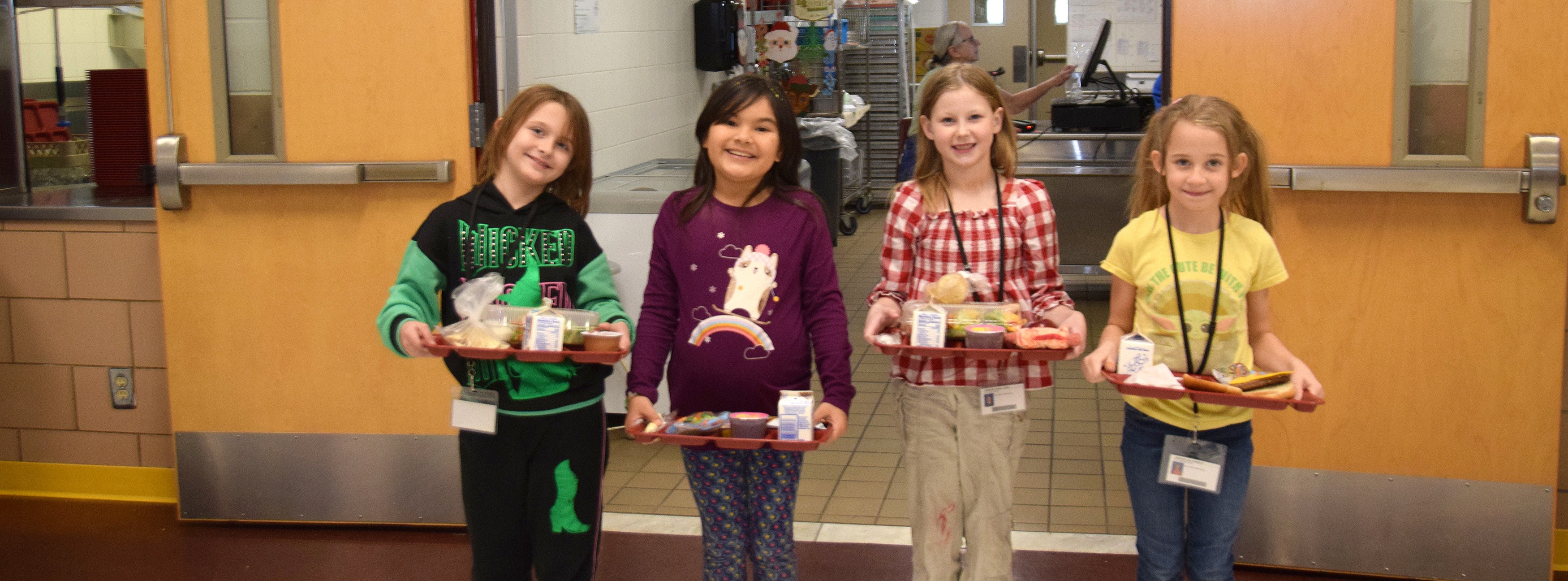 Four friends hold their lunch trays in the cafeteria at Caryl E. Adams Elementary