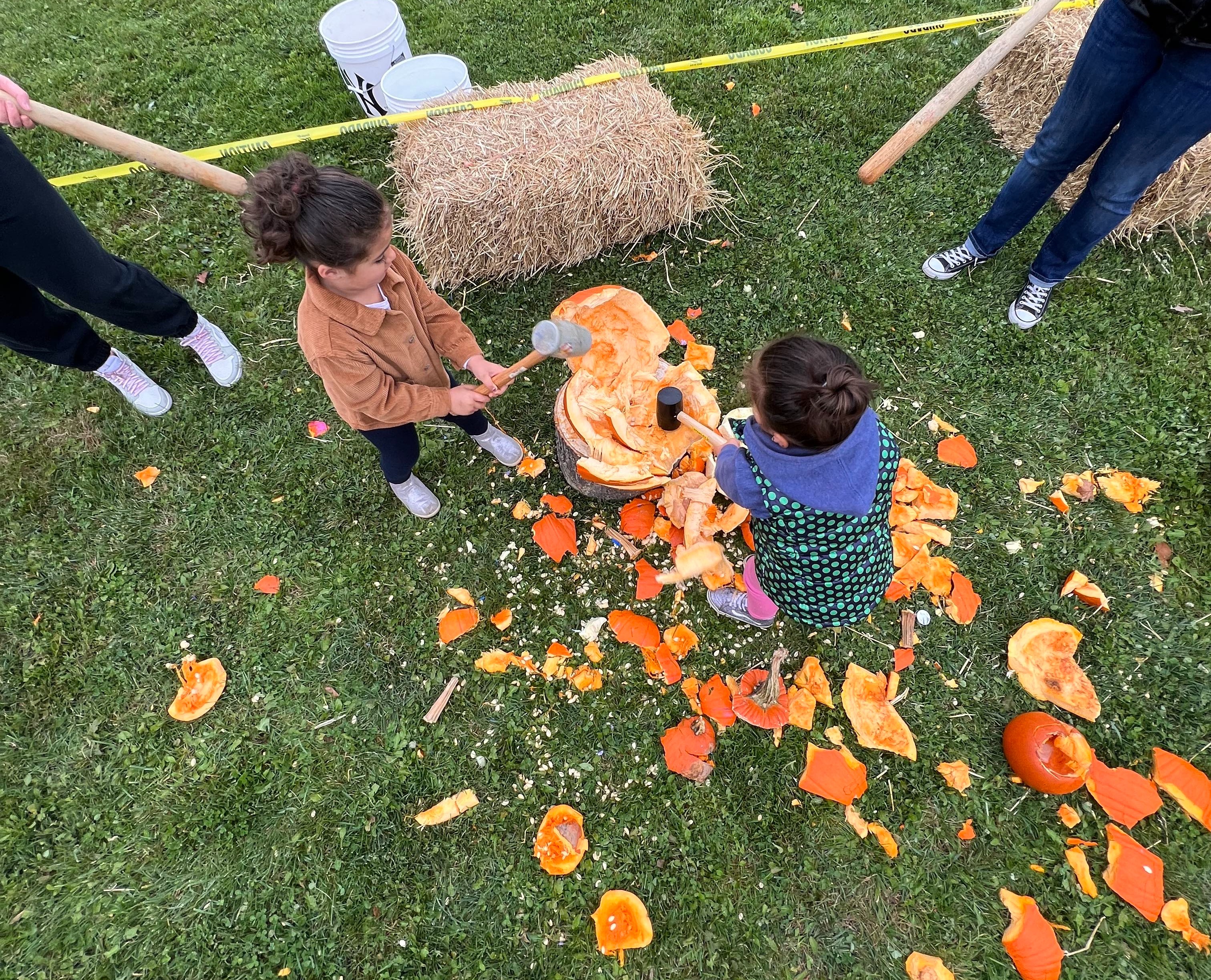 two students smash pumpkin with mallets