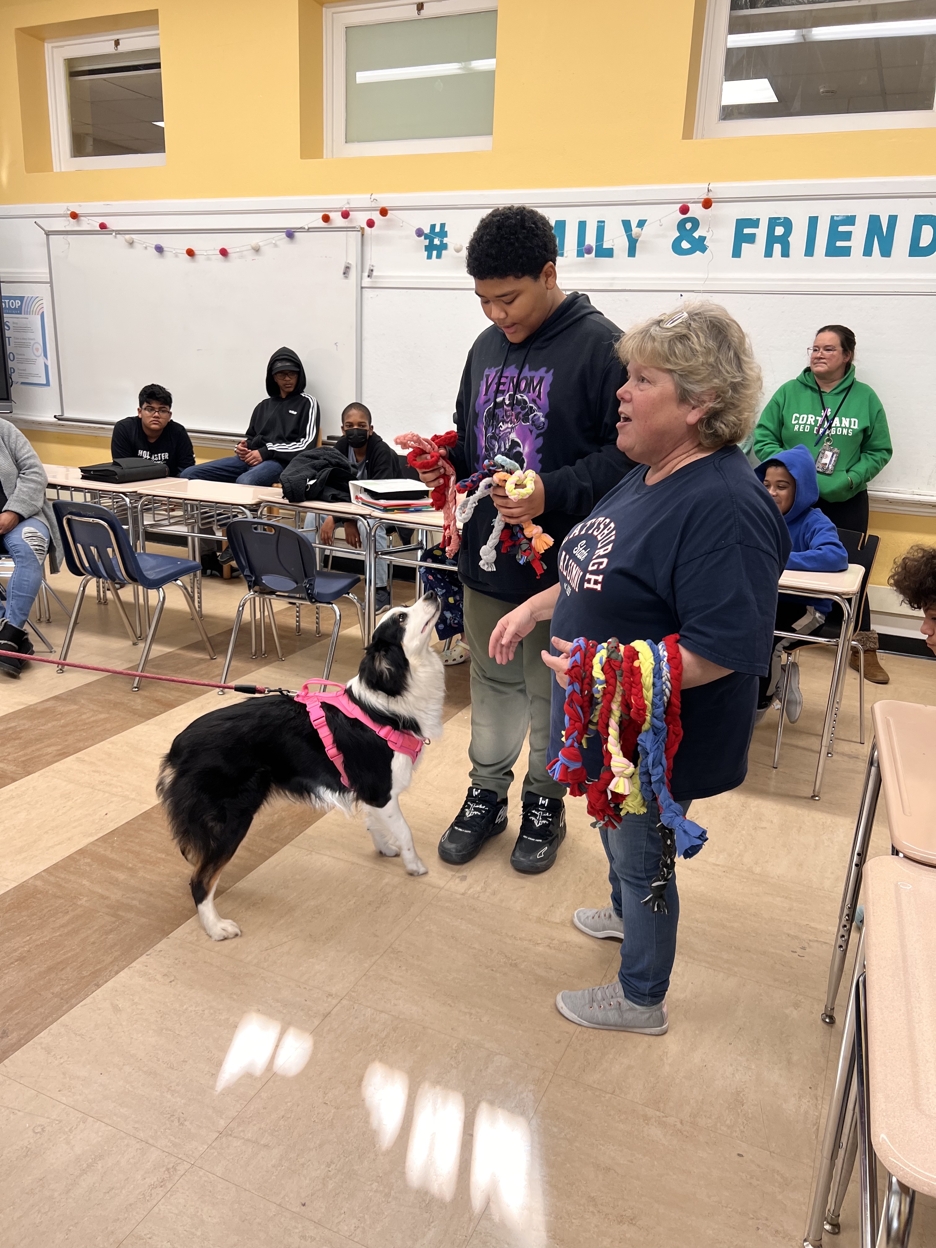 student and teacher present shelter dog with homemade toys