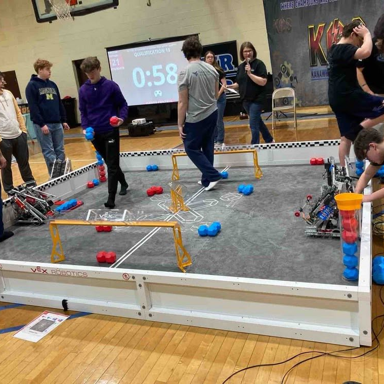 A gymnasium with a team of people on a raised platform with a robot competition.