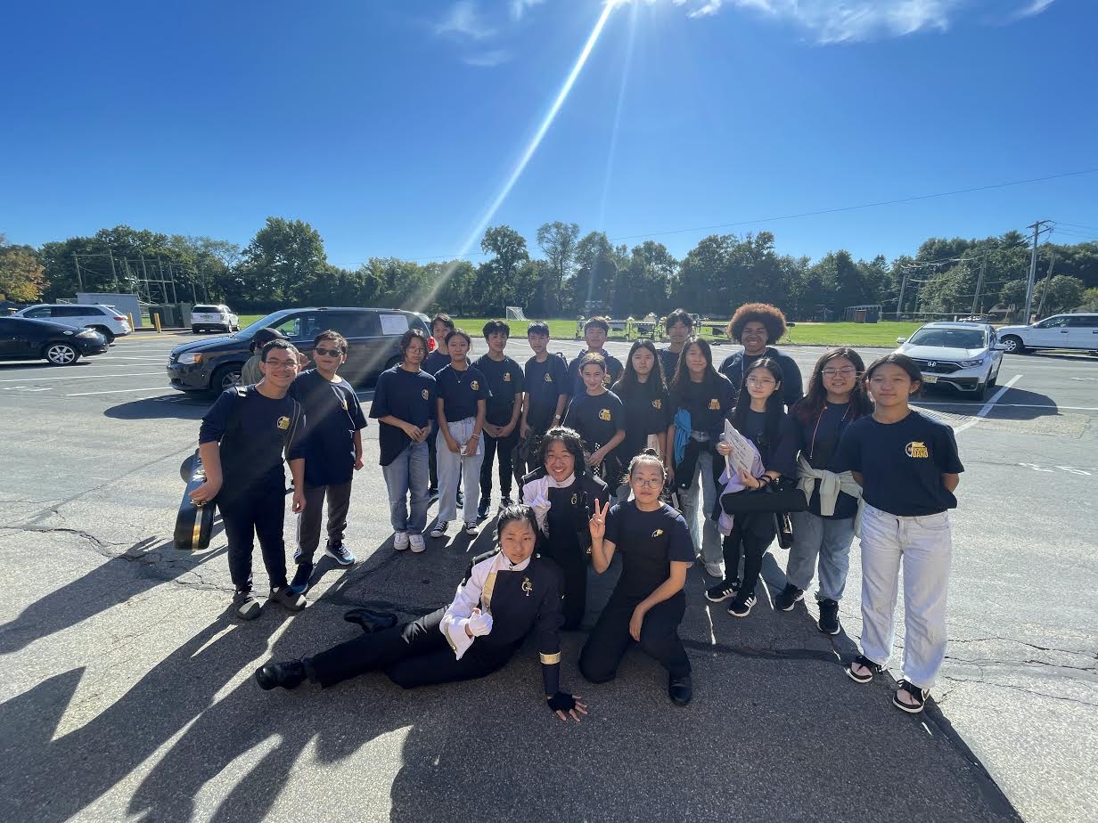 Harrington Park alums and 7th and 8th Grade Band students standing outside on a bright and sunny day, after playing America the Beautiful with the NVOT Marching Band at their home competition on September 24, 2022.