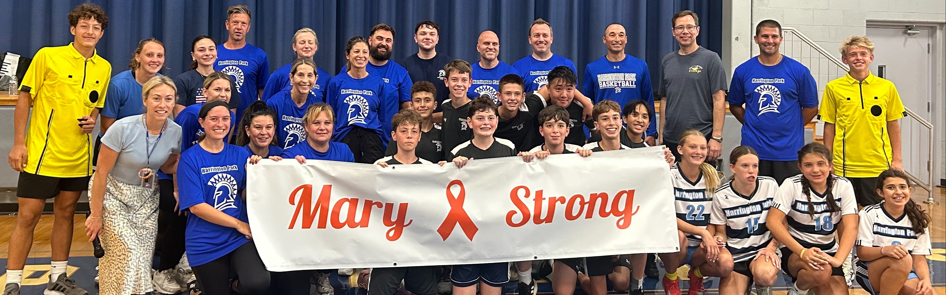 Students and Staff Posing with a Mary Strong Banner after a soccer game fundraiser for the Urban Family