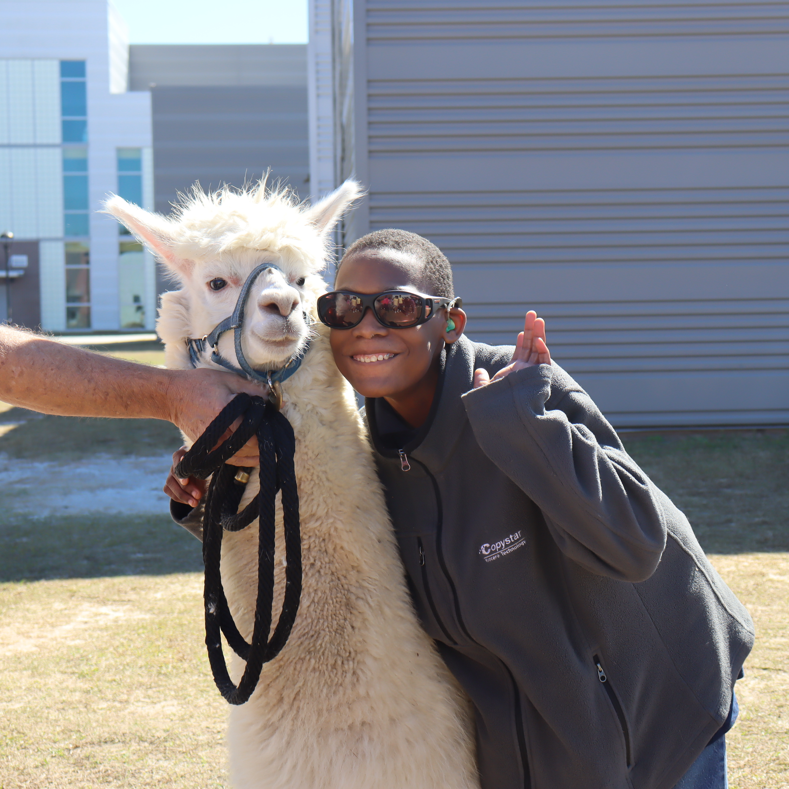 Student smiling beside lama during CTAE event