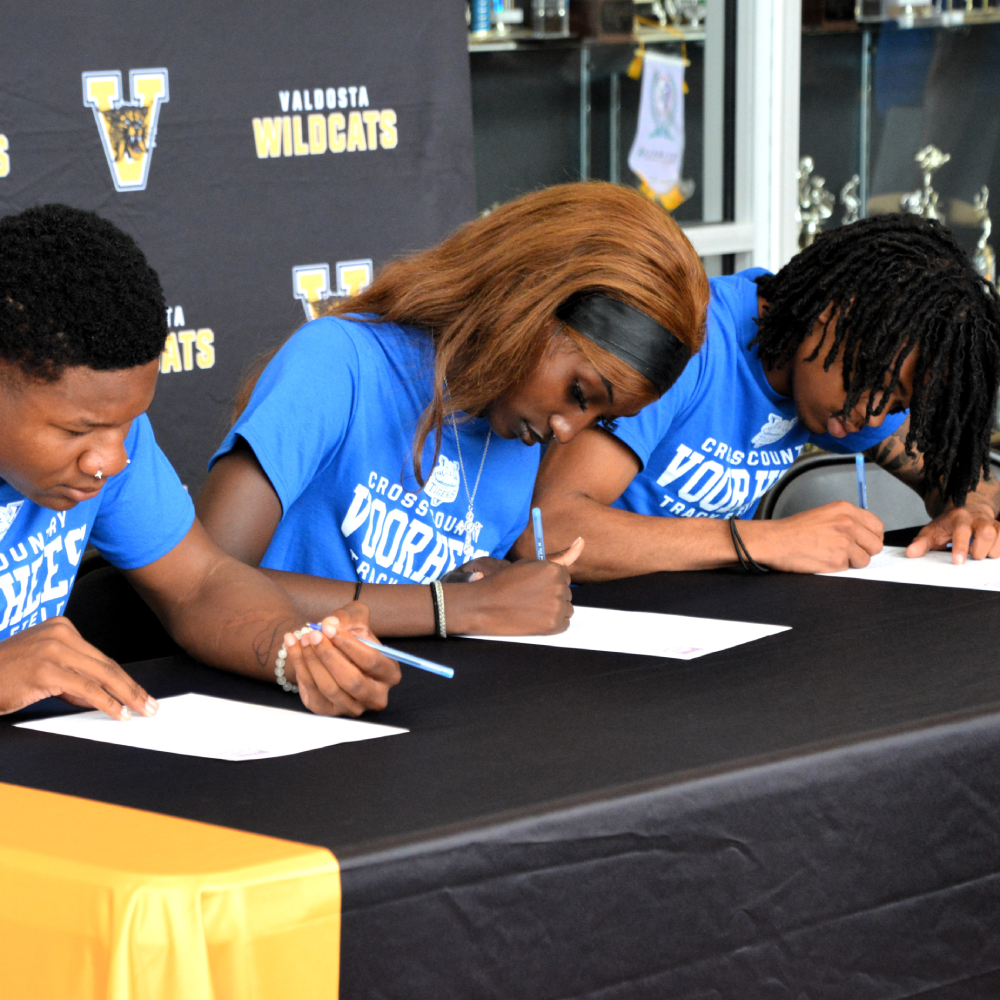 three students signing for athletic scholarships