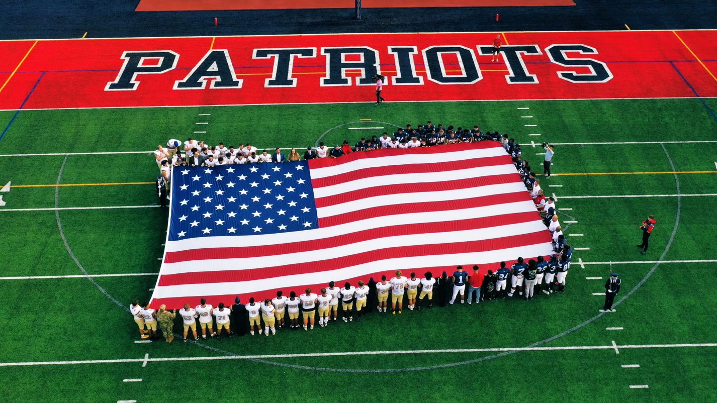 Drone photo of football teams holding american flag