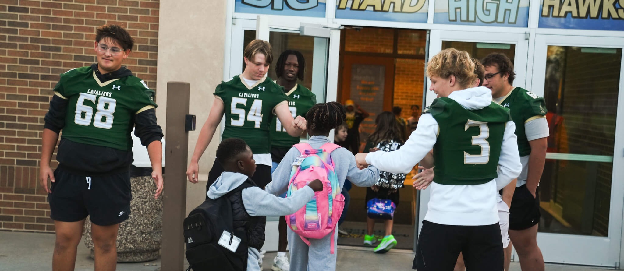 Happy Jefferson football players greet excited incoming elementary kids before the morning bell.