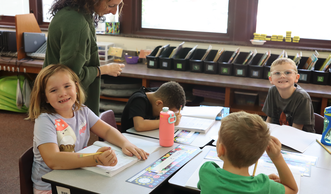 little girl sitting at desk with her classmates