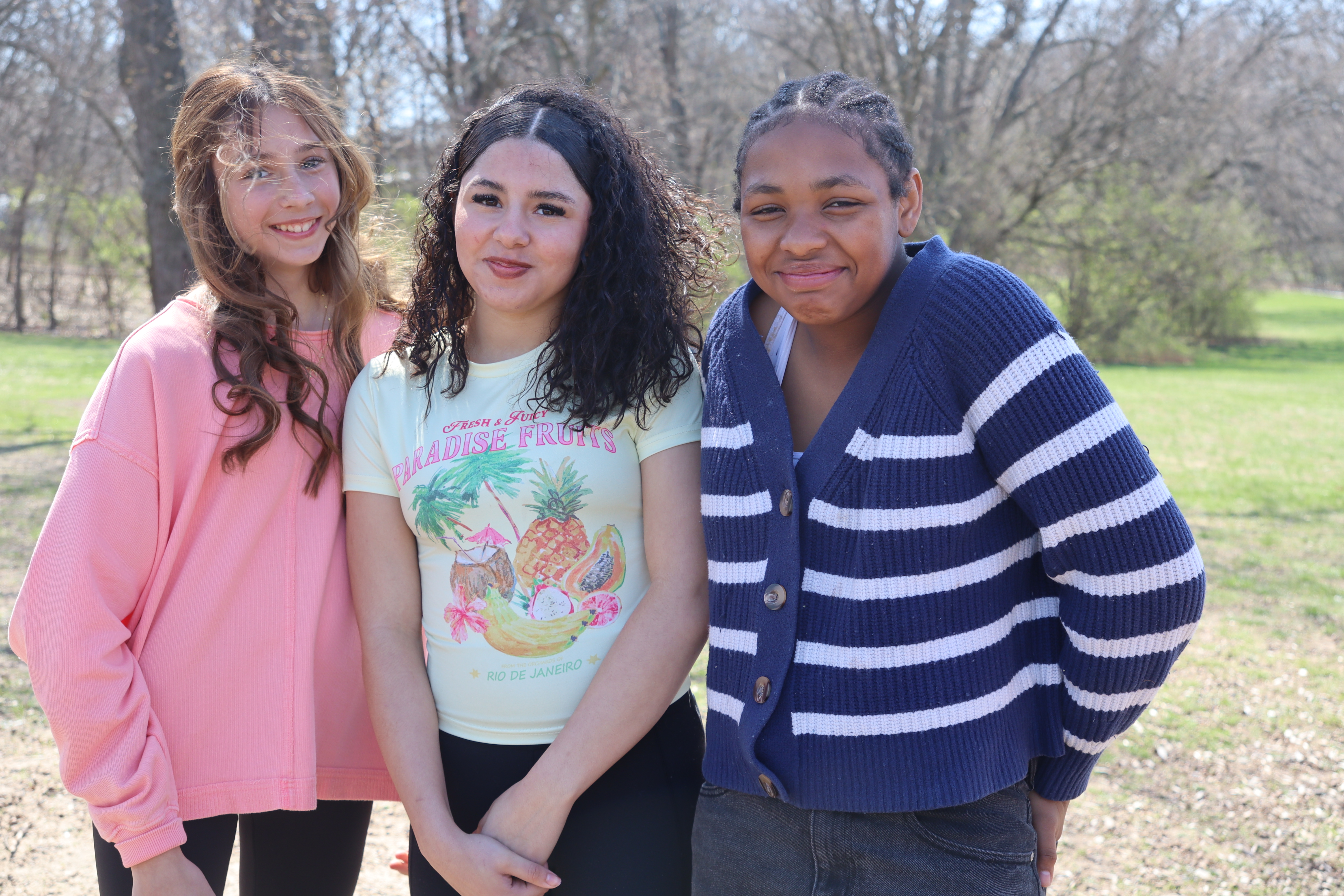 three young girls standing on playground looking at camera