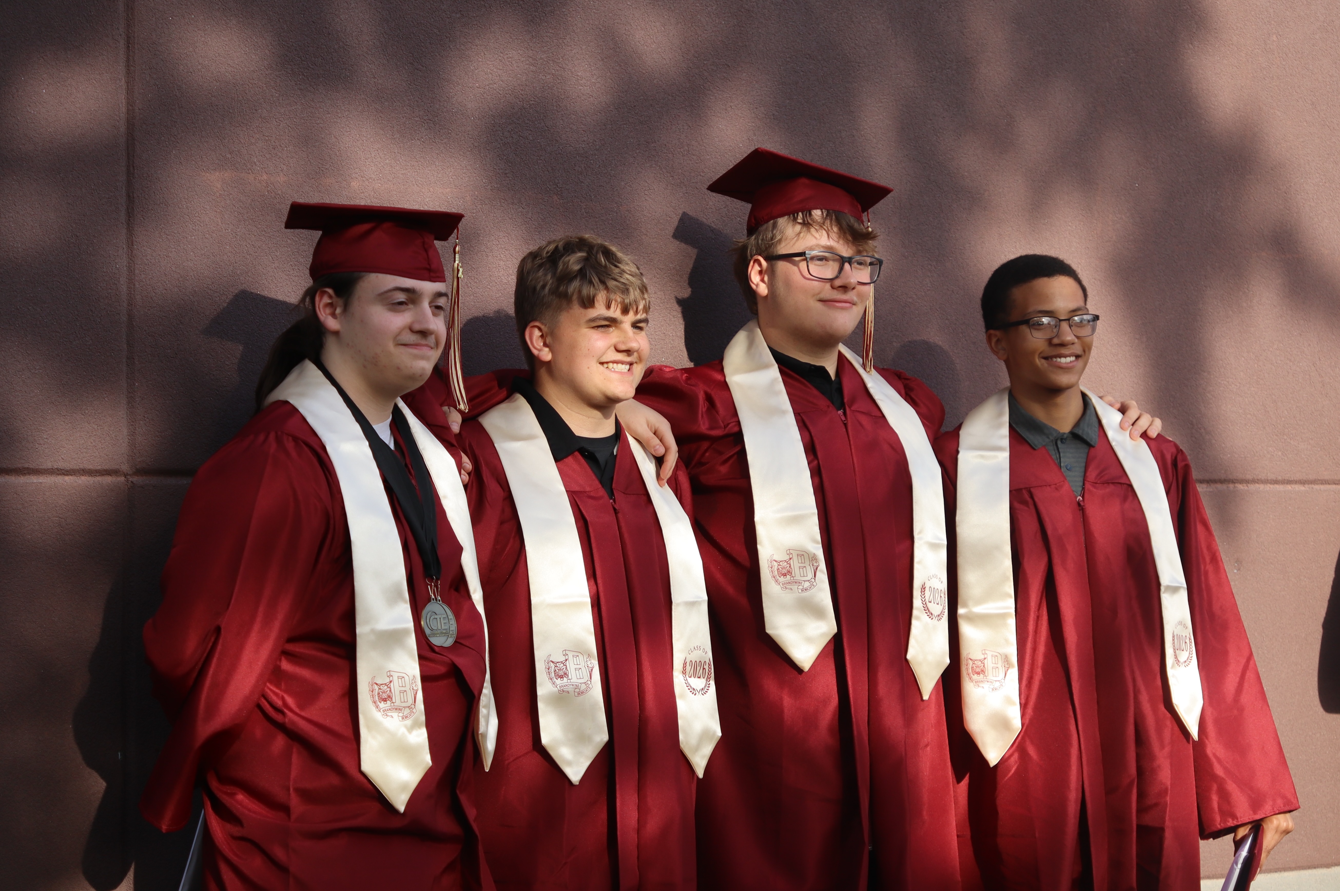 group of 4 male graduates standing outside for a picture