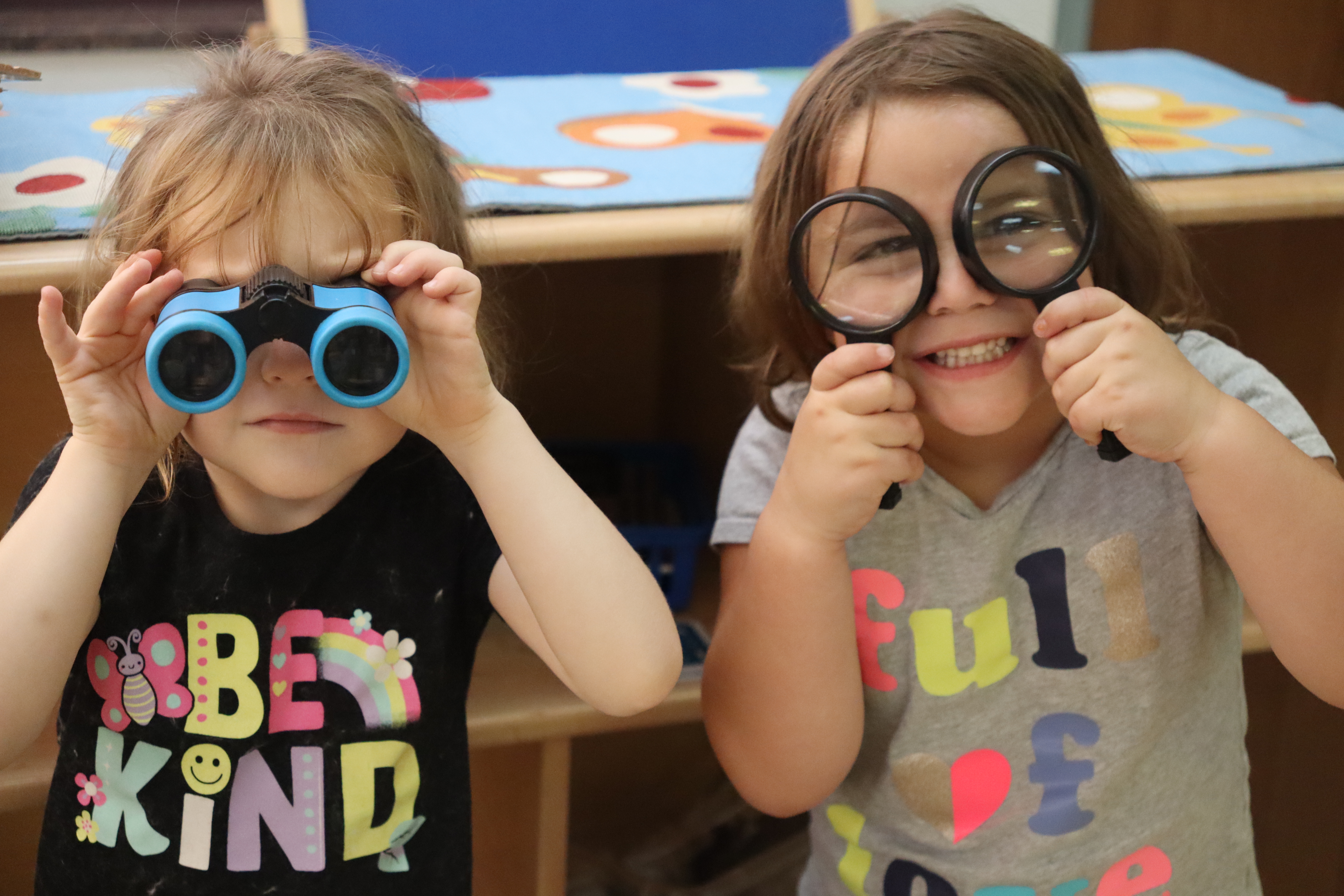 two little girls looking through binoculars and magnifying glass