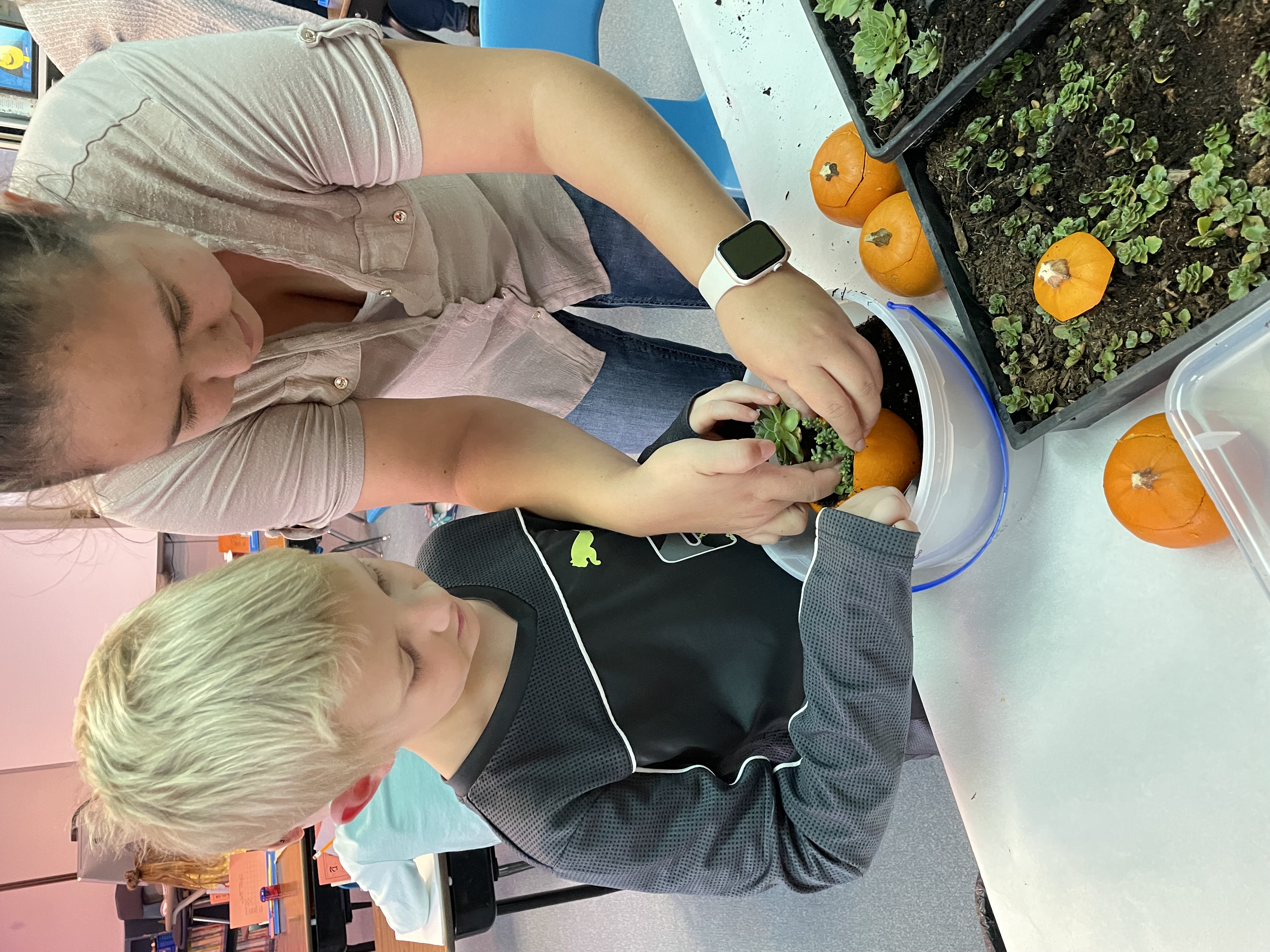 Student and teacher planting in a hollowed out orange fruit