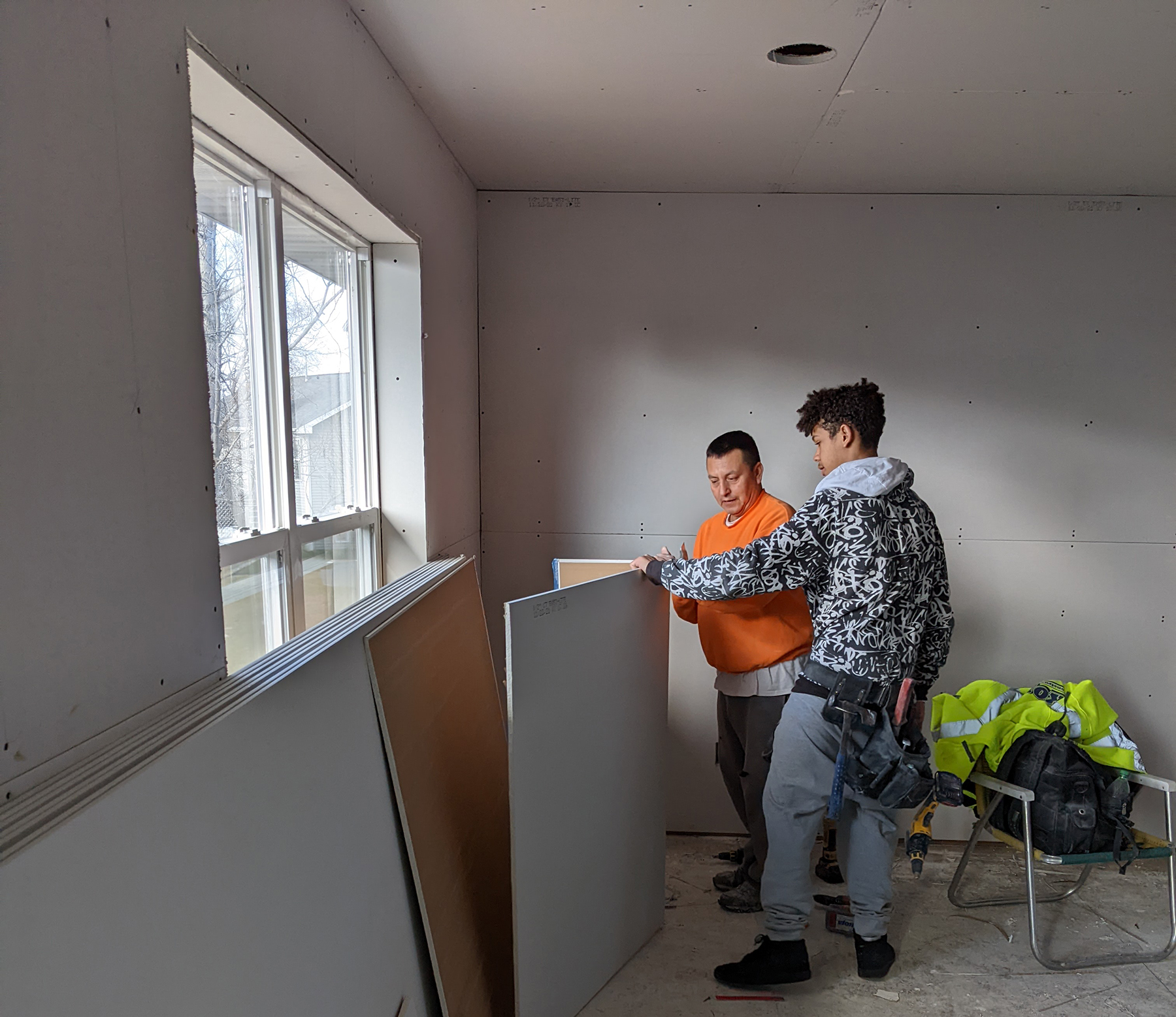 Youthbuild student installing drywall