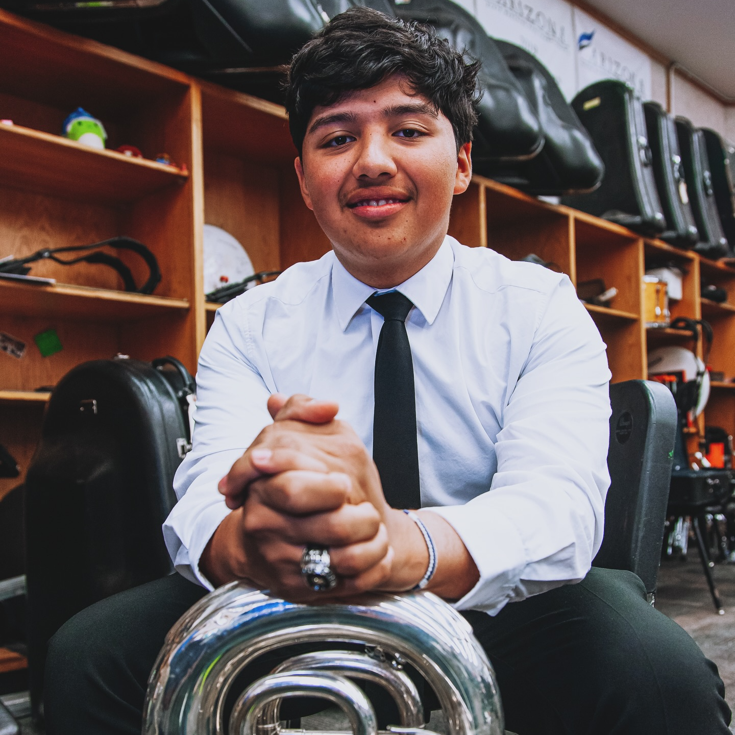 Isaac sites in front of a wall of instruments in their cases