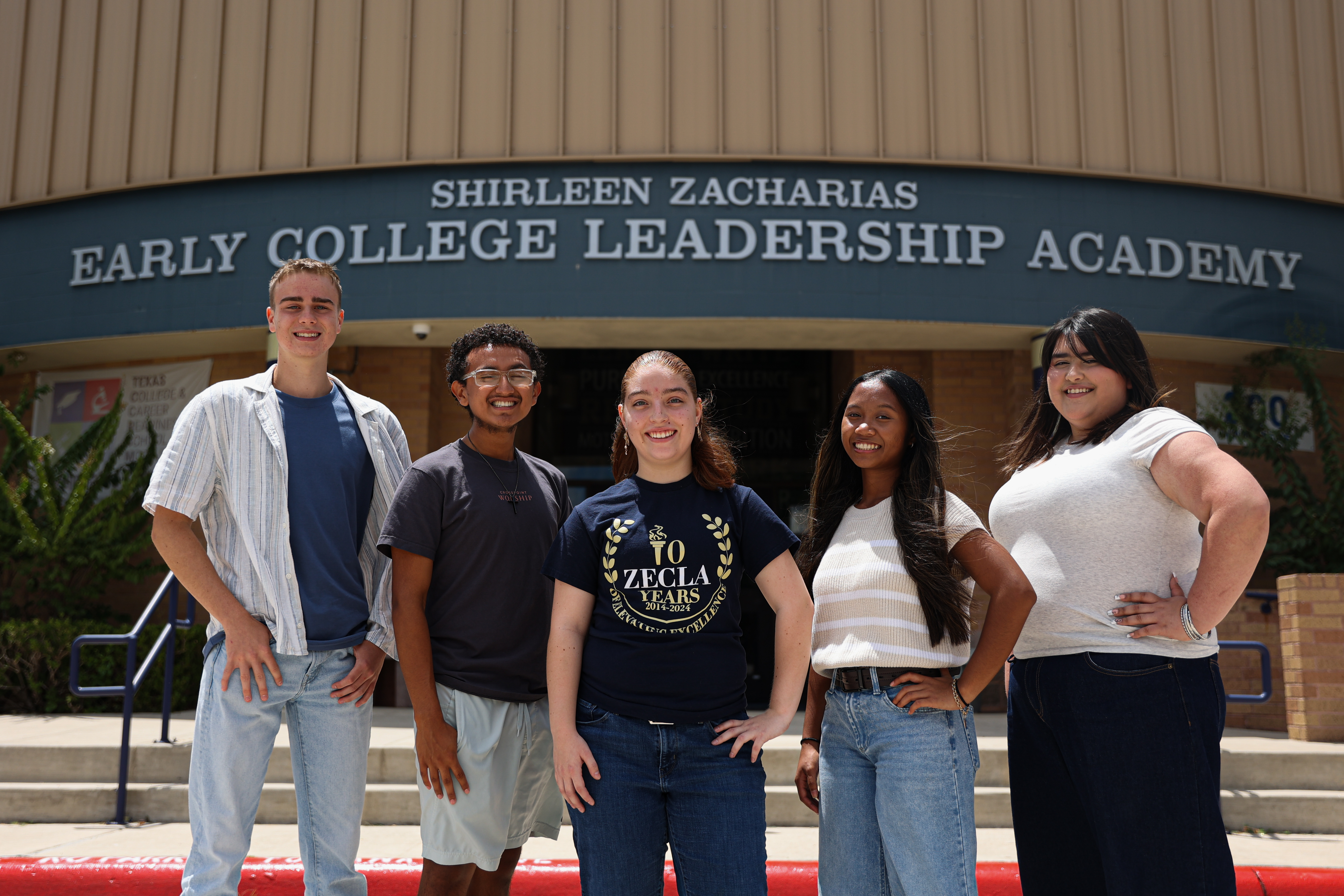 Group of students posing in front of school
