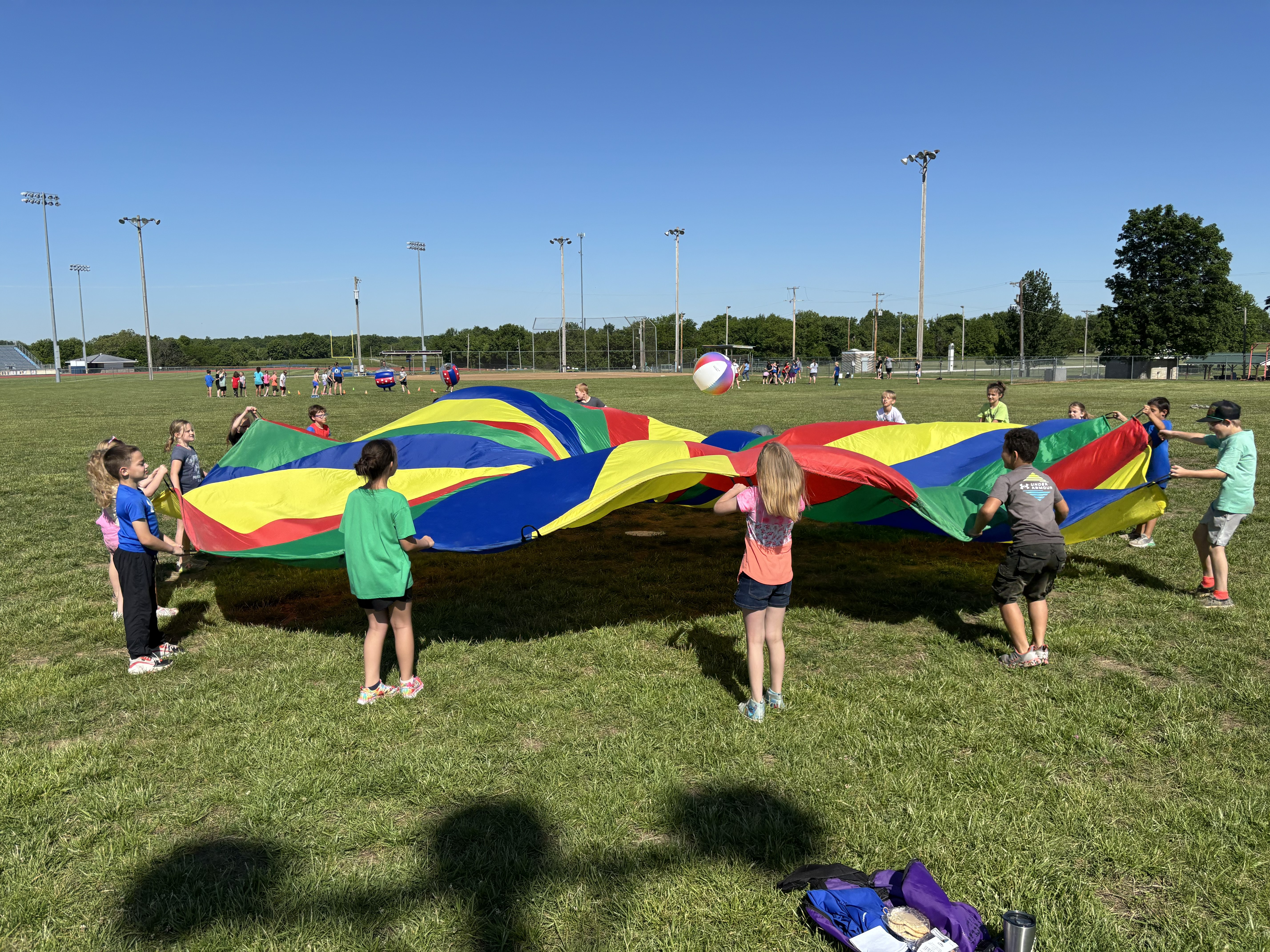 Elementary students using the playground parachute on field day.