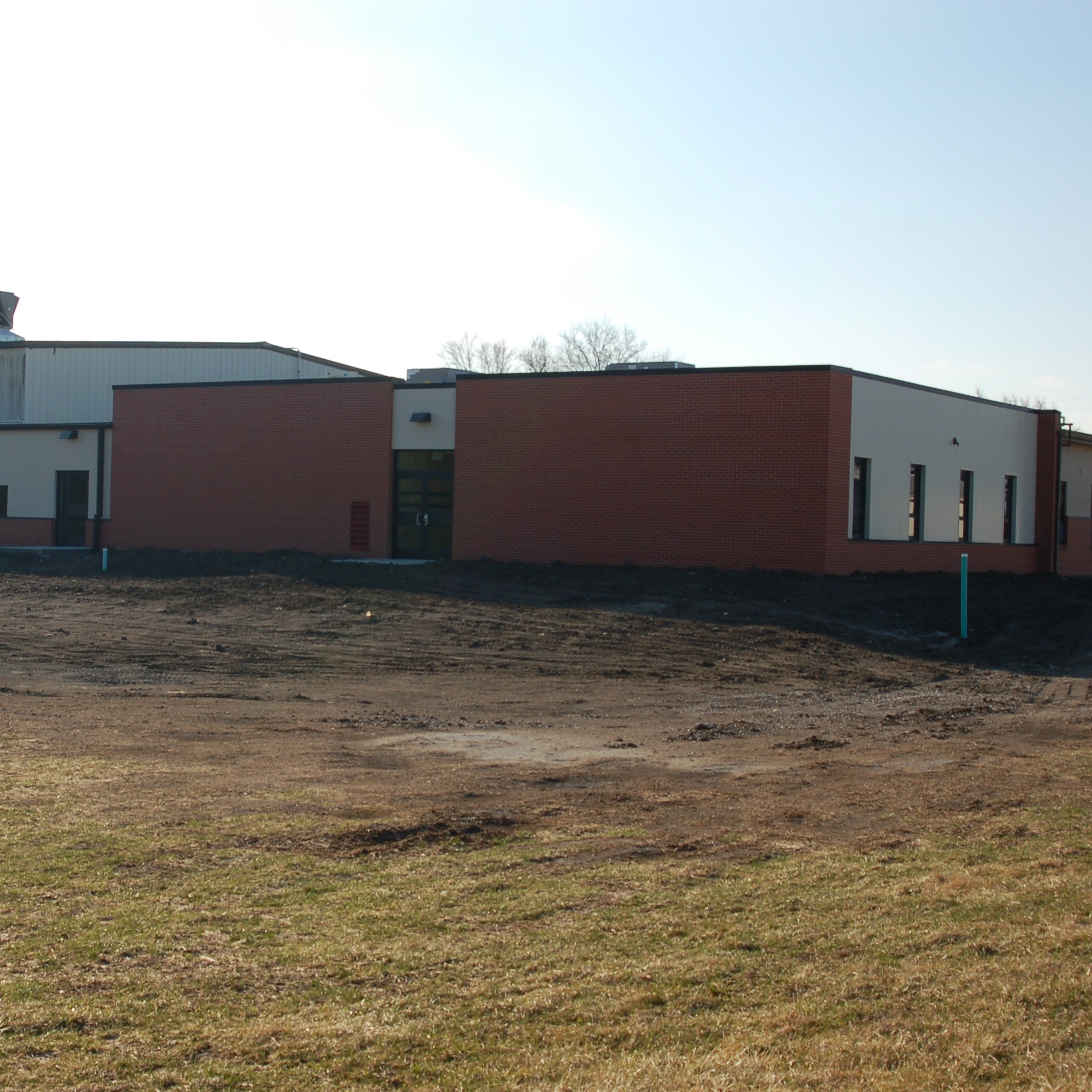 A building with red and white exteriors, two doors, and a large open field in front.