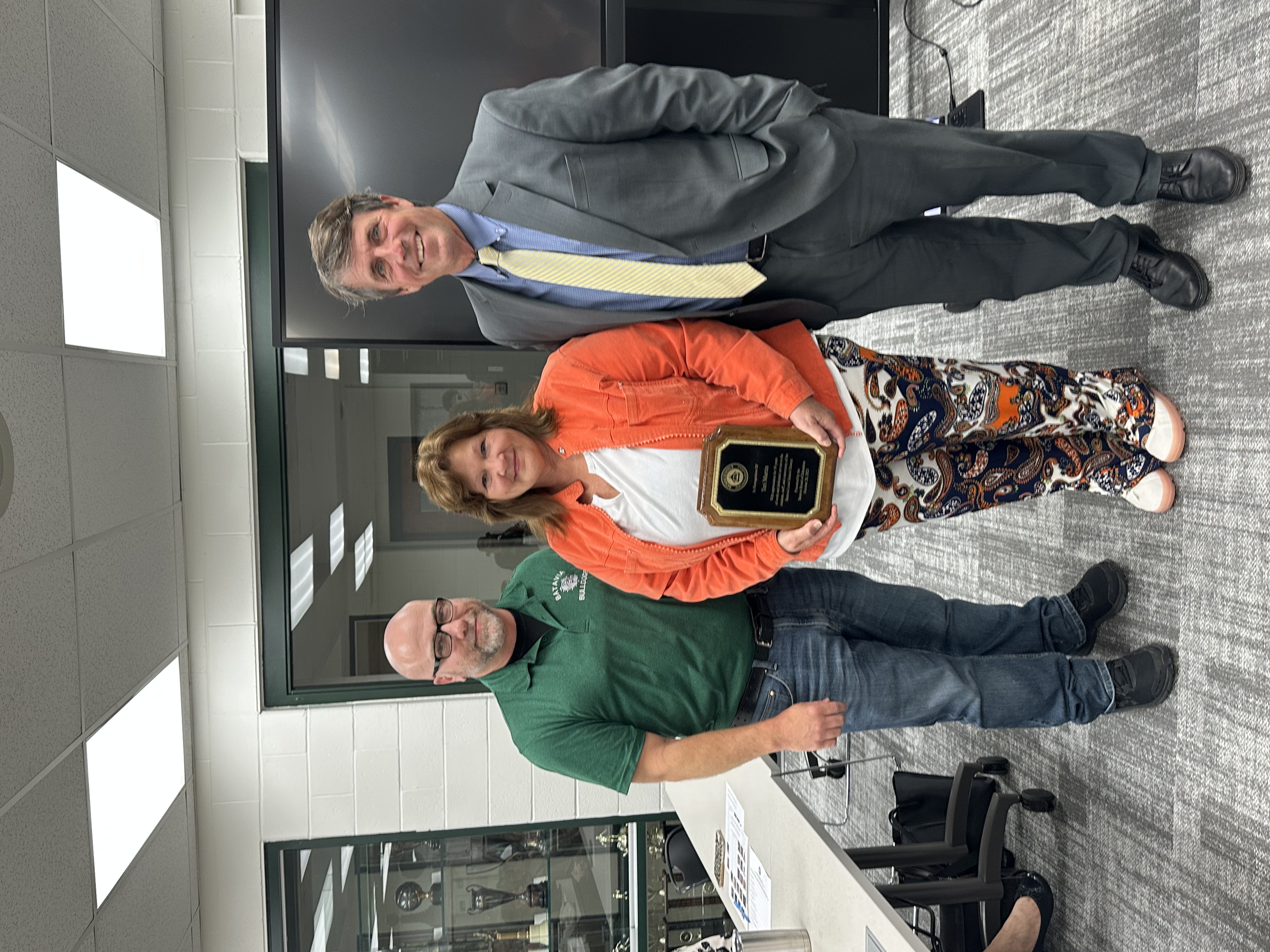 image of Teri Martin holding a plaque being recognized by director of transportation Shawn young and superintendent Keith Millard