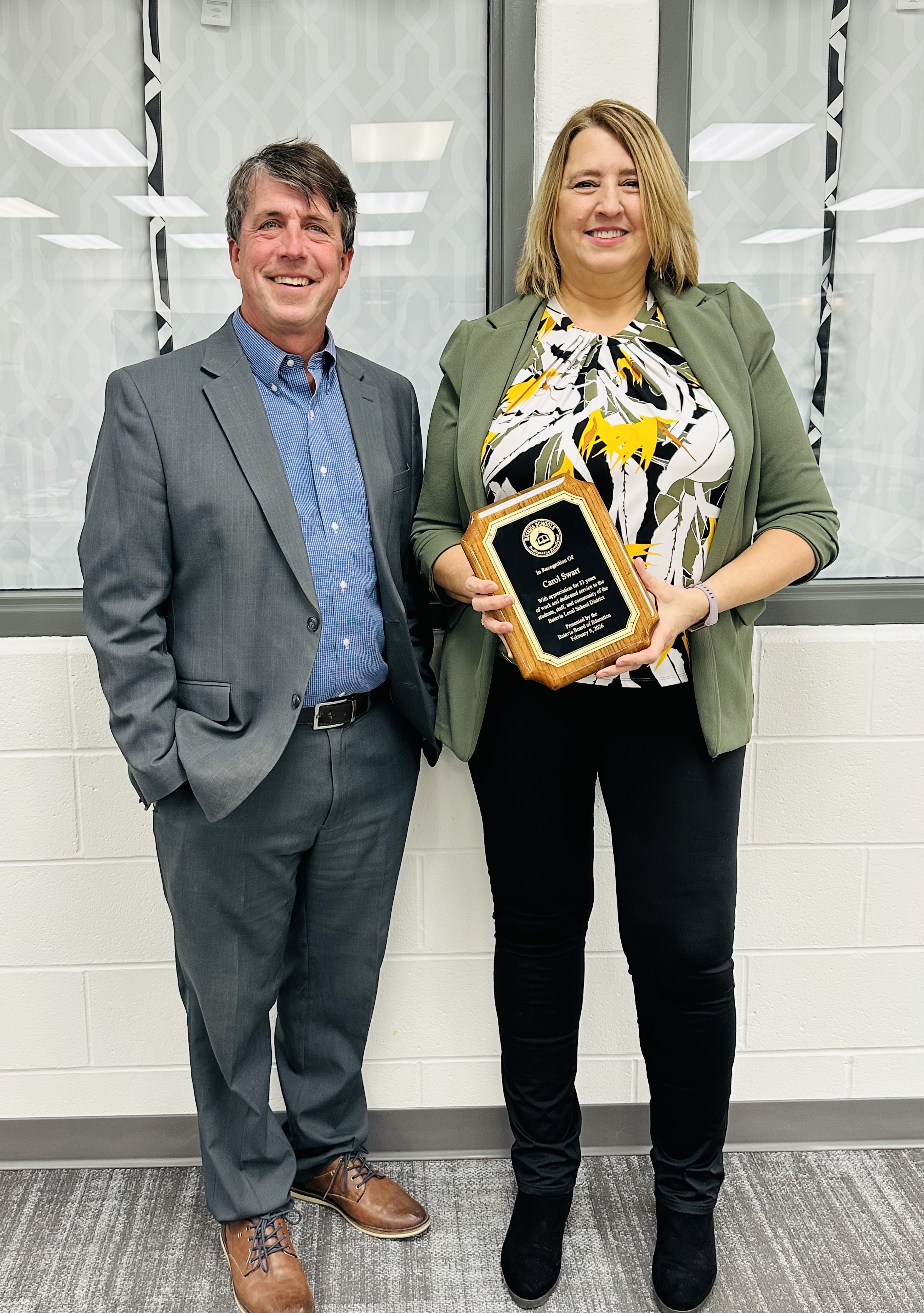 Carol Swart and Keith Millard with Carol Swart holding a plaque honoring her retirement from the Batavia Local School District