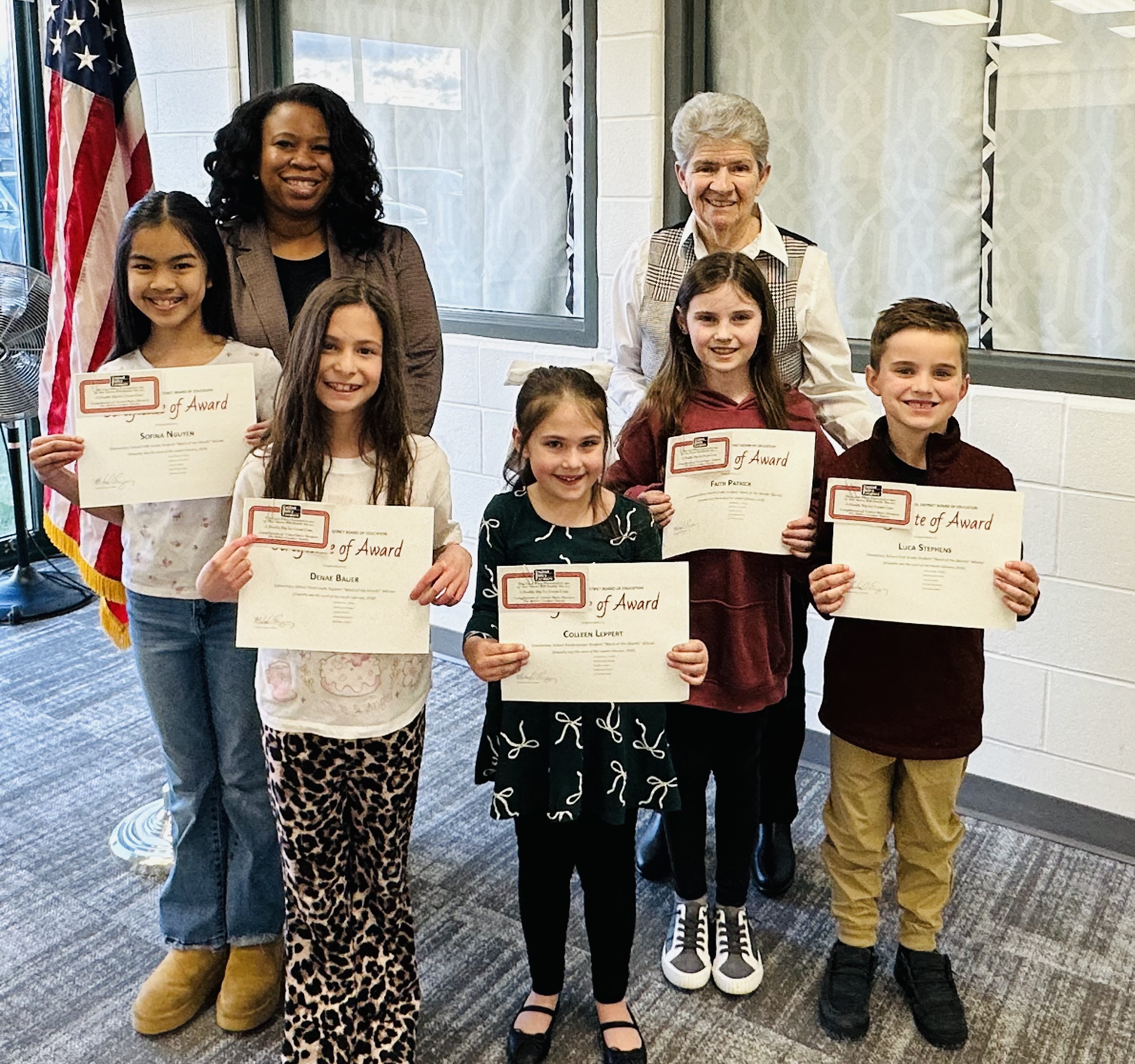 February word of the month students from batavia elementary school holding a certificate of achievement with board members barb Bruner and Michelle Eiland