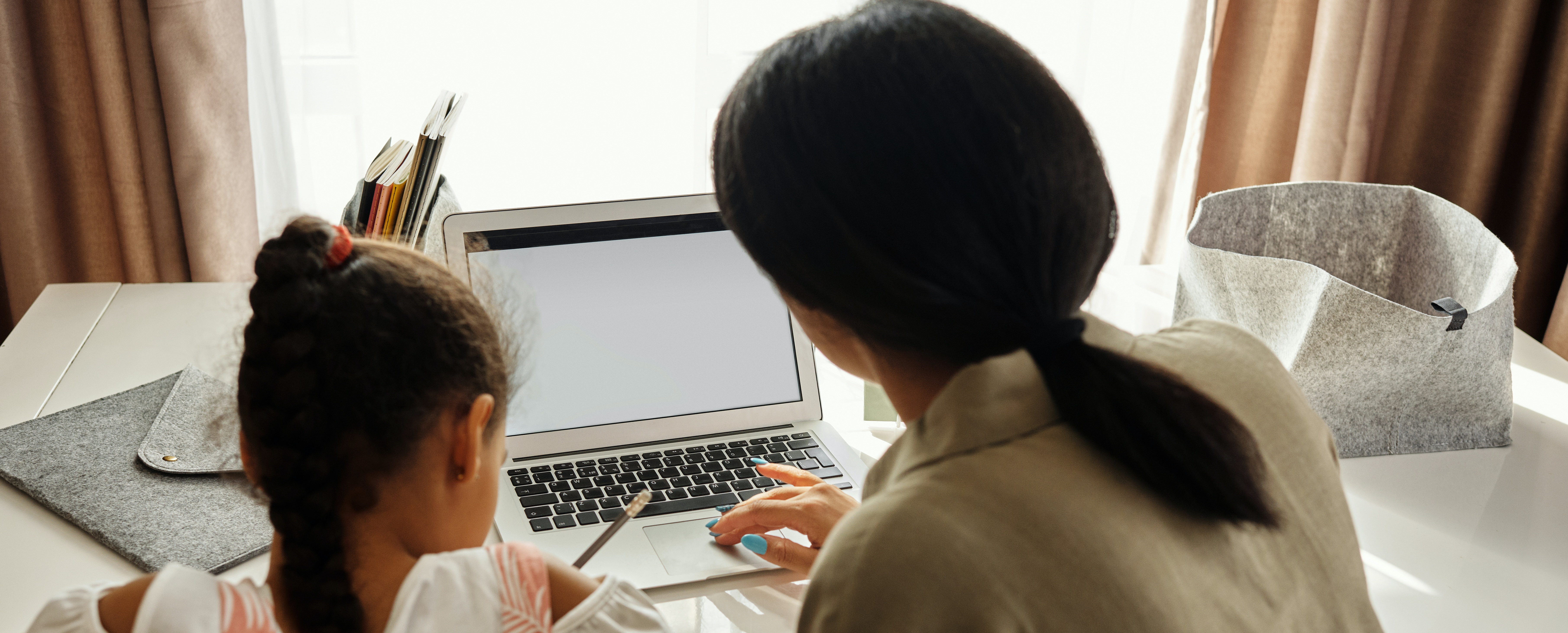 mother helping daughter at computer
