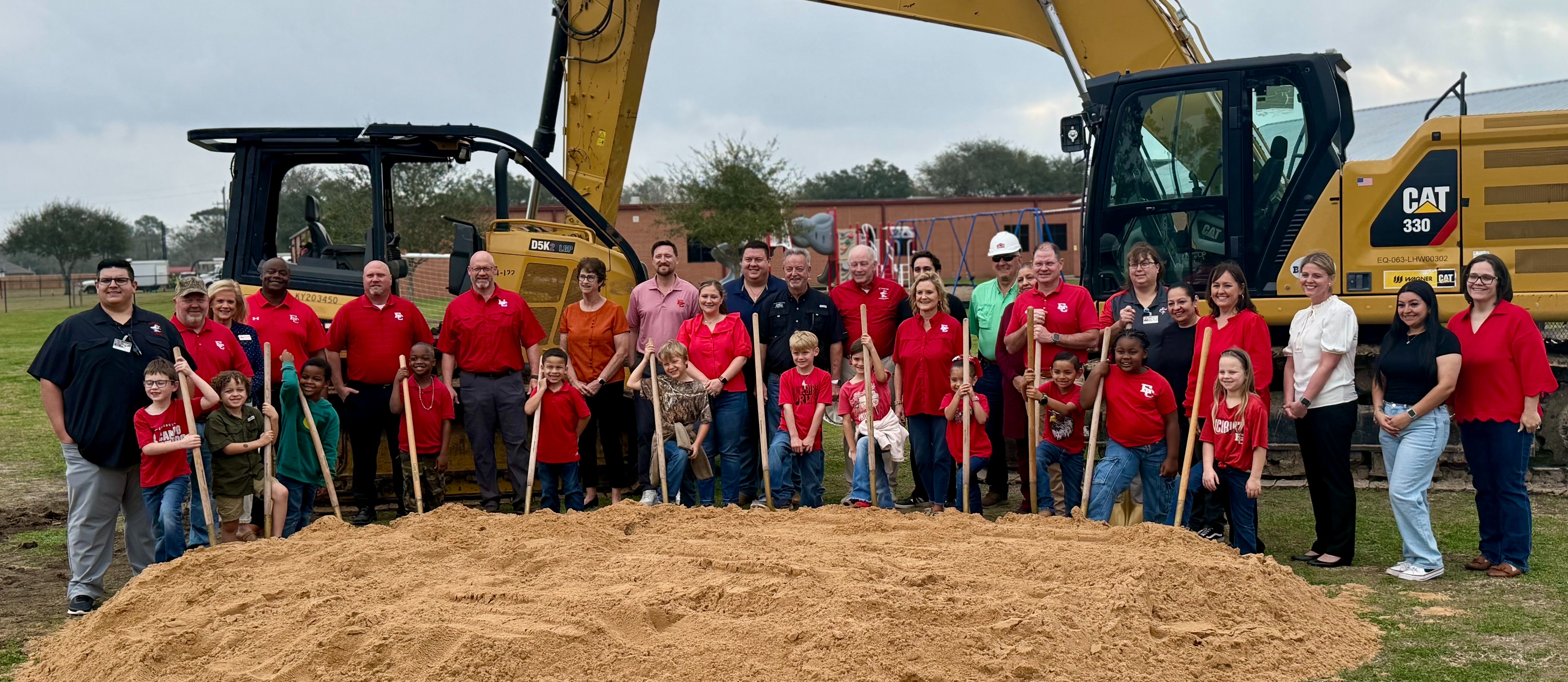 kids, community members, and ECISD representatives with shovels behind a pile of dirt