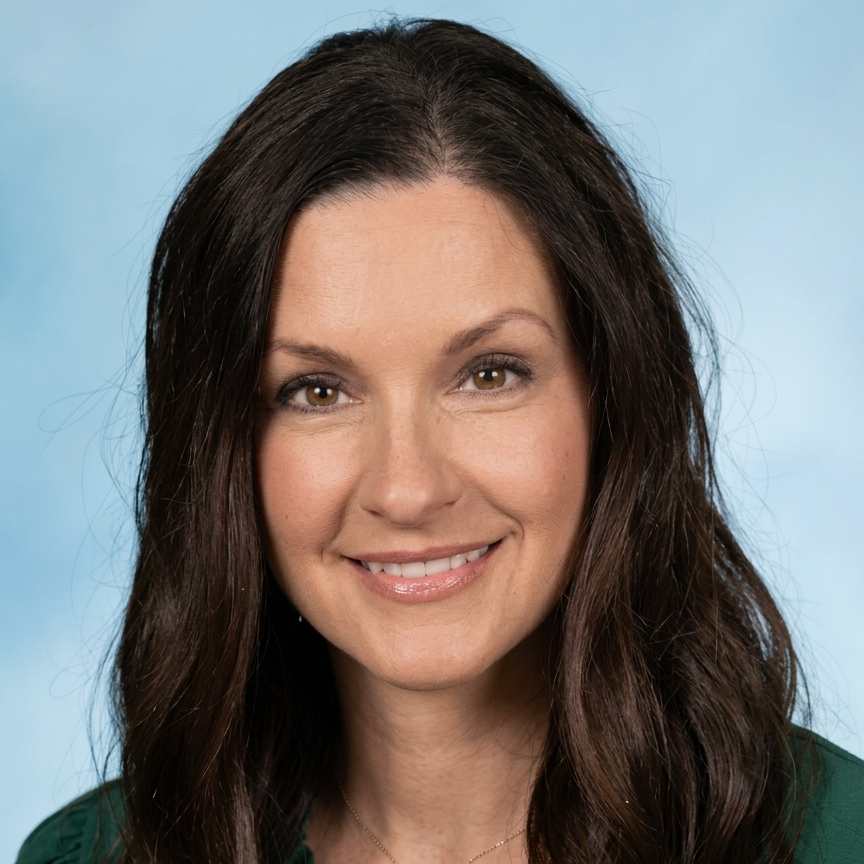 A woman with long brown hair smiles in front of a blue backdrop