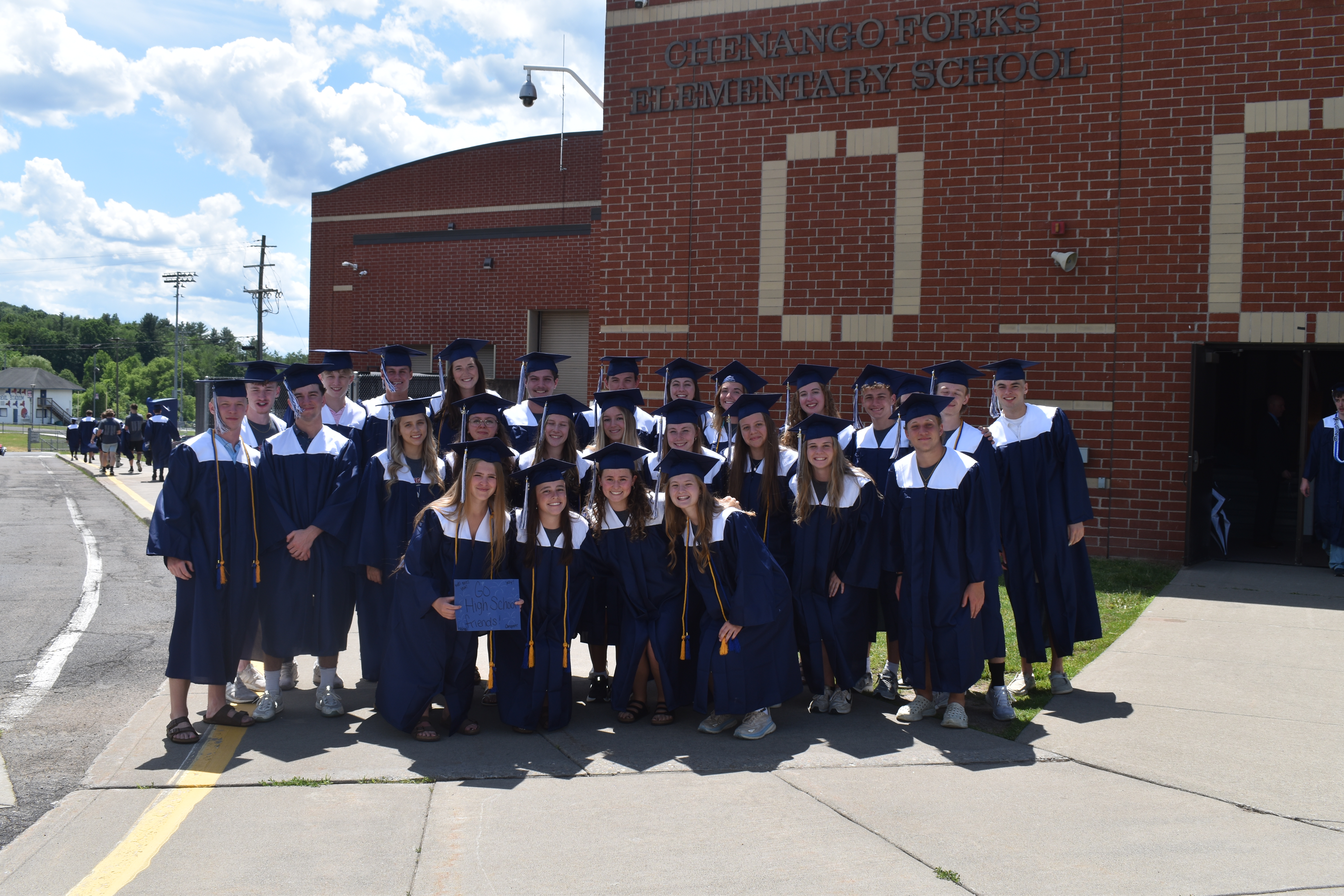 SENIOR CLASS IN CAP AND GOWNS OUTISDE ELEMENTARY SCHOOL