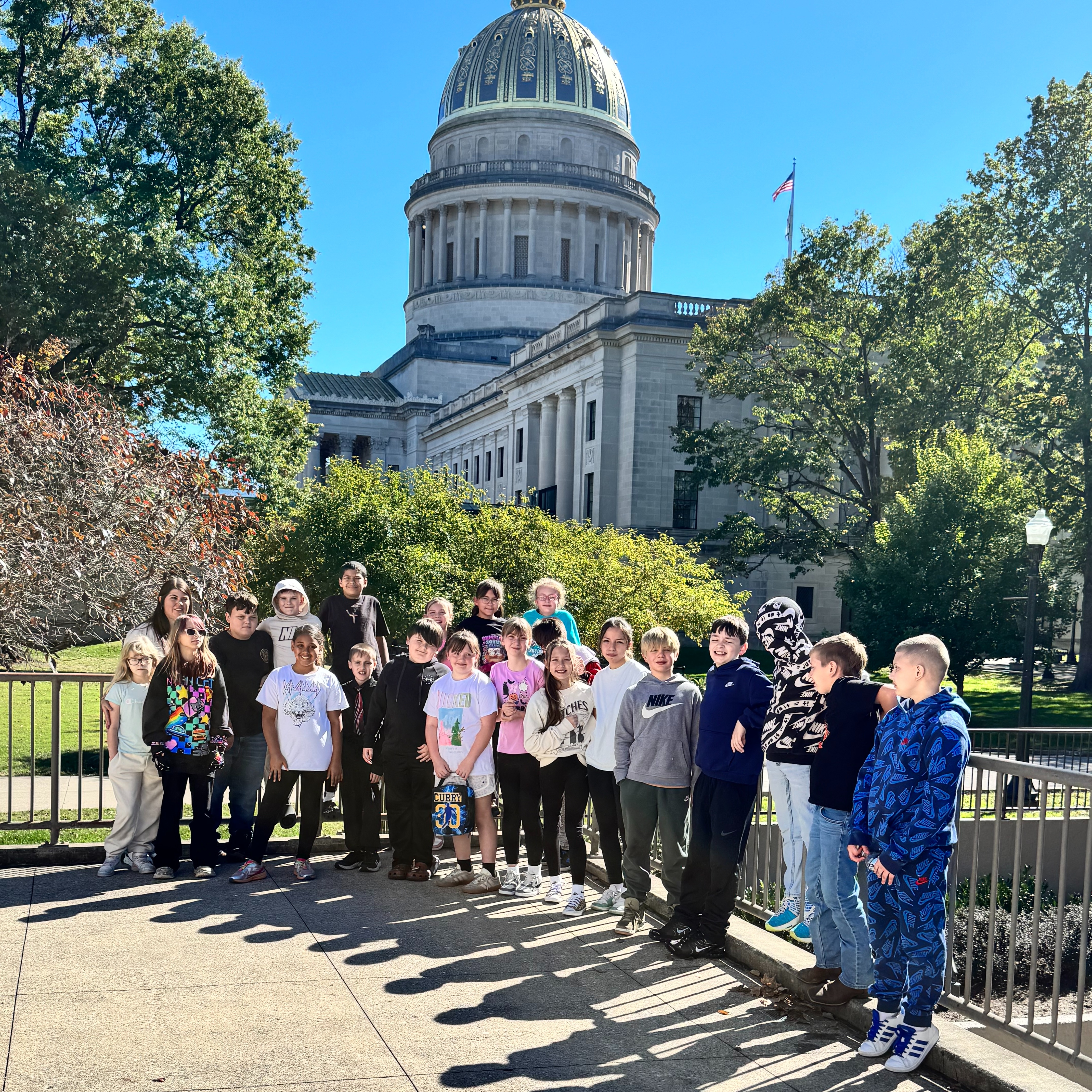 Students gathered in front of a building with a dome roof and a fence.