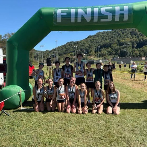 A group of young people posing in front of a green arch with the word 'FINISH'.