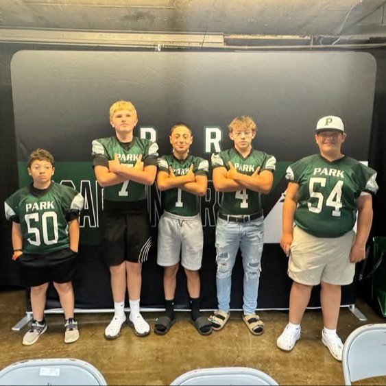 Five young males in green jerseys with numbers 50, 4, 7, 54, and P standing in front of a backdrop.