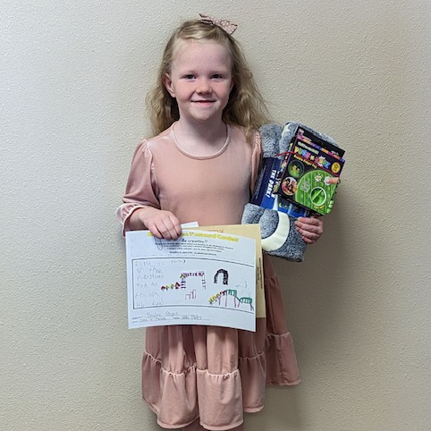 Image of kindergarten girl holding a picture and blanket