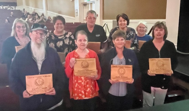 image of retiring teachers holding a wooden plaque with their name