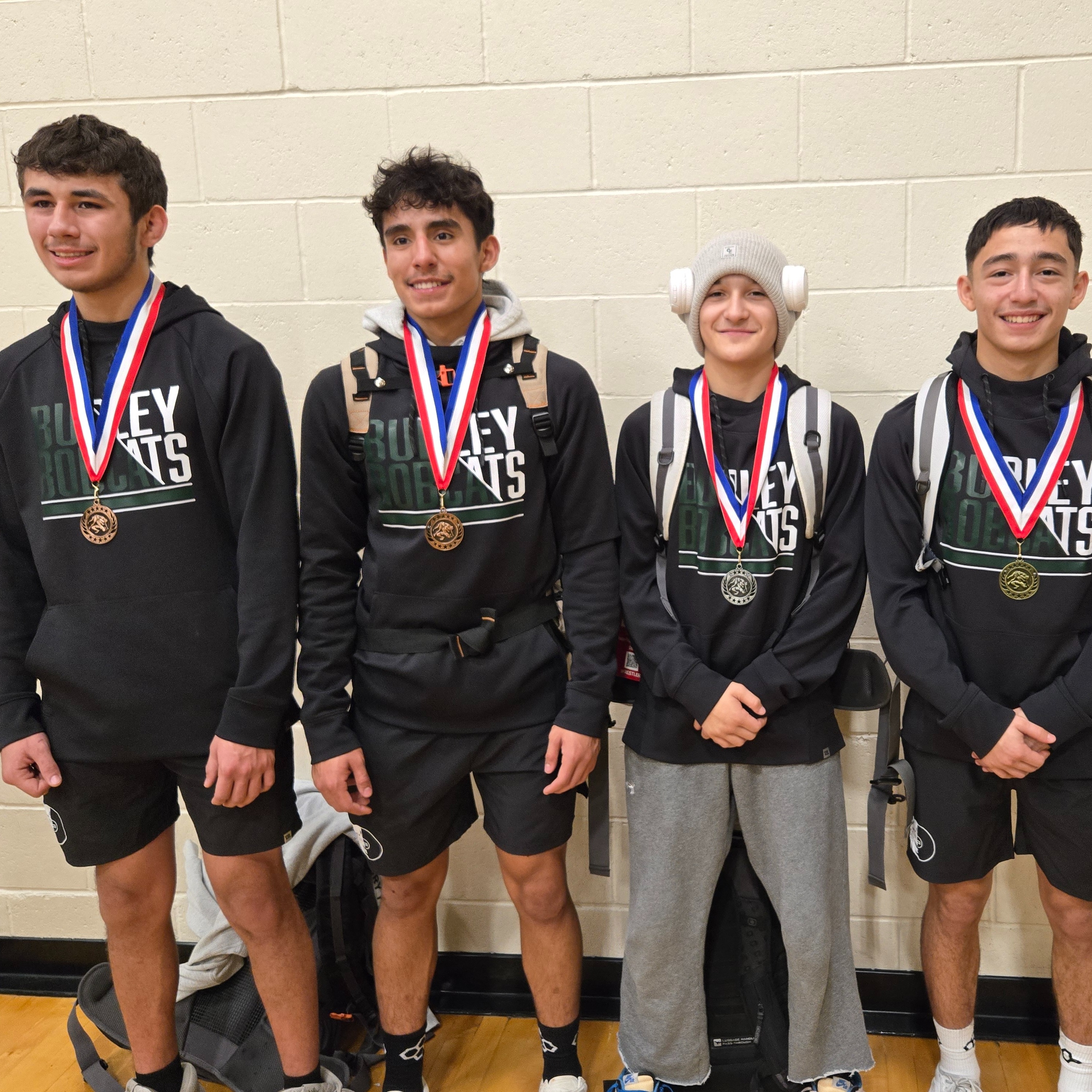 4 high school wrestling team members showing medals they won at competition